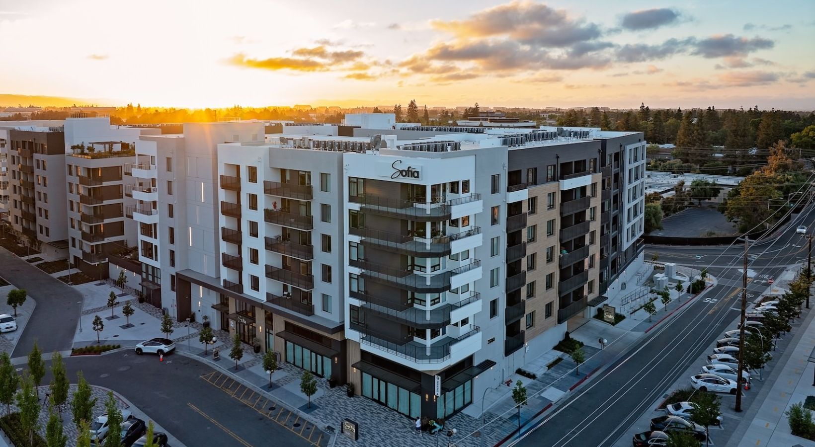 Aerial view of a modern apartment complex at sunset with white and gray buildings and balconies at Sofia in Santa Clara, CA.