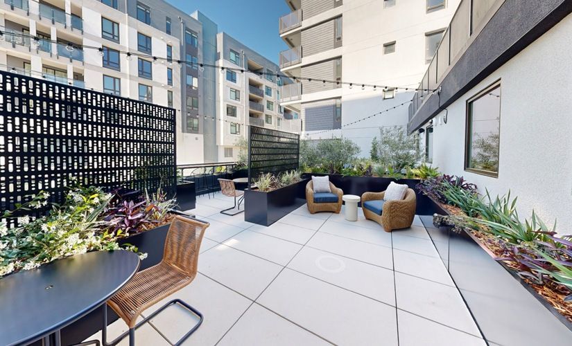 Outdoor communal terrace with seating, planters, and string lights in a modern apartment complex at Sofia, offers  pet-friendly apartments in Santa Clara.