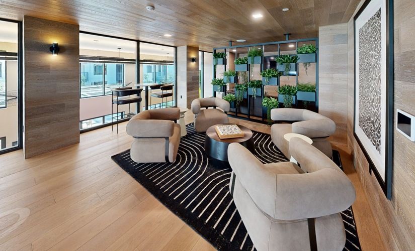 Modern community lounge with beige seating, a rug, and a plant wall at Sofia, offers  pet-friendly apartments in Santa Clara.