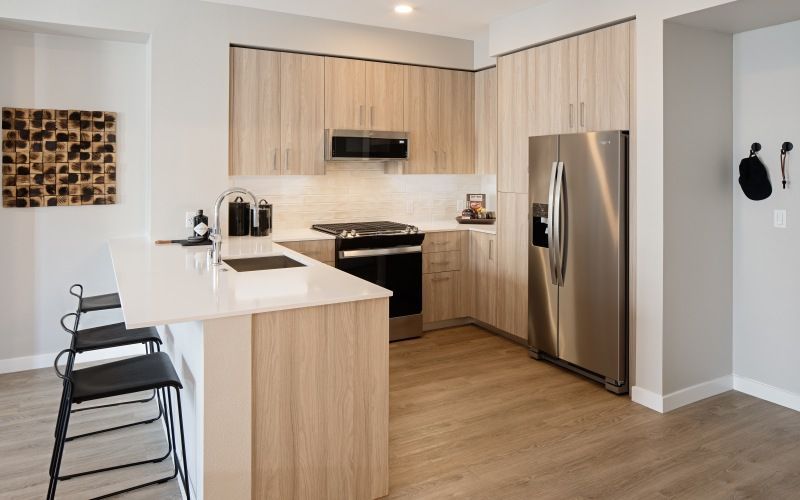 Modern apartment kitchen with an island, stainless steel fridge and stove, and light wood cabinets at Sofia, offers  pet-friendly apartments in Santa Clara.