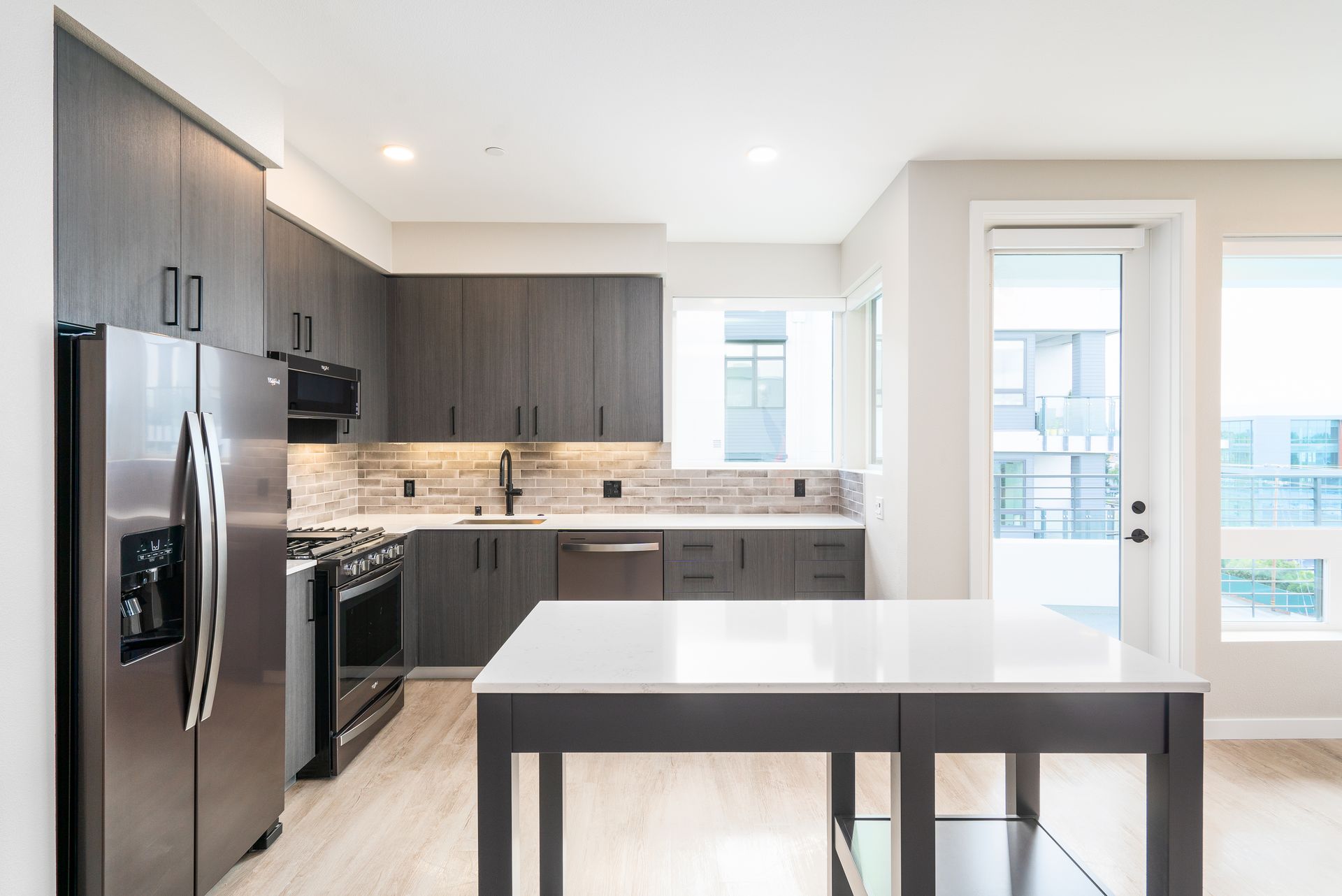 Modern kitchen with gray cabinets, stainless steel appliances, and a white island at Sofia, offers apartments in Santa Clara.
