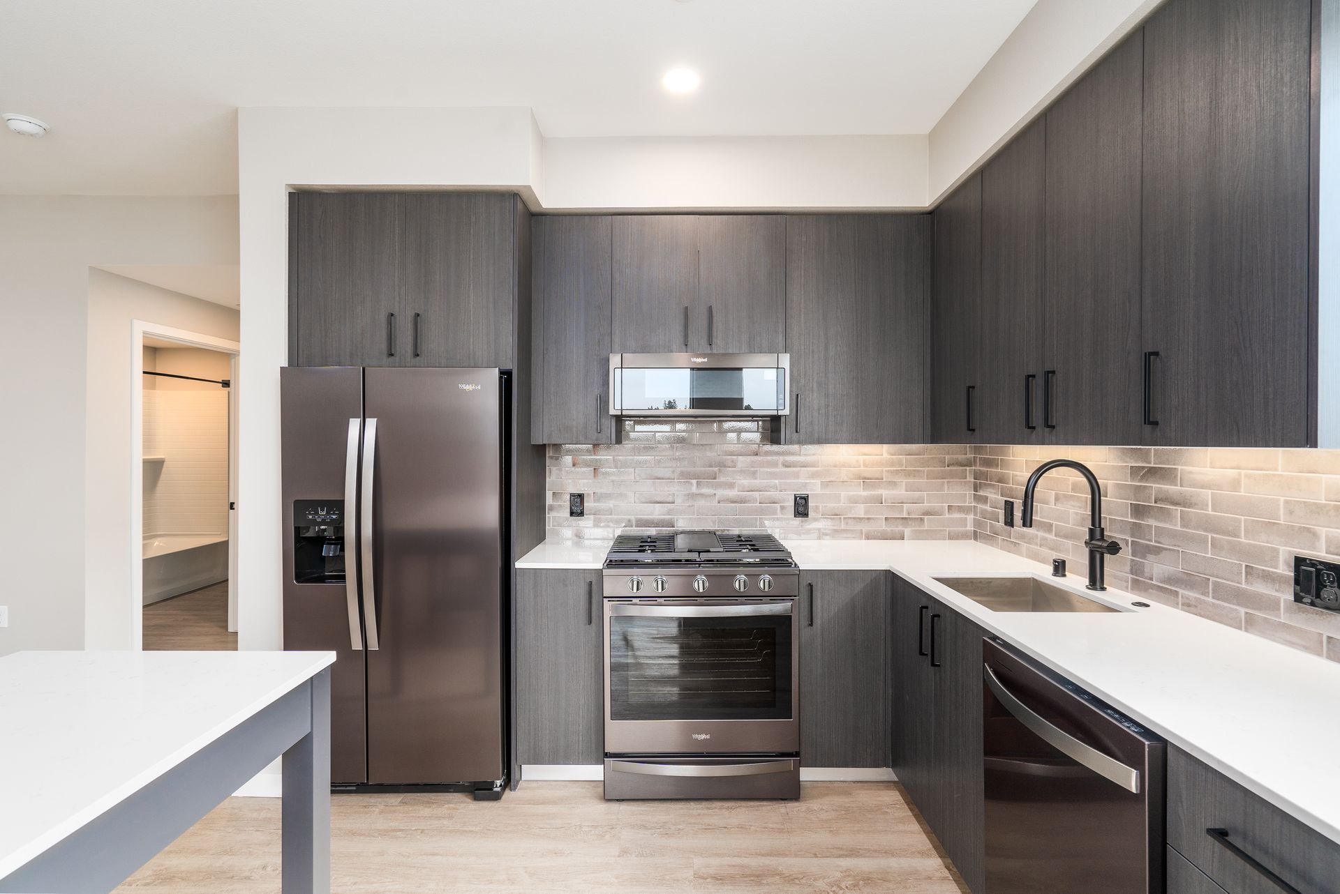 Modern kitchen with dark gray cabinets, stainless steel appliances, and white countertops at Sofia, offers apartments in Santa Clara.