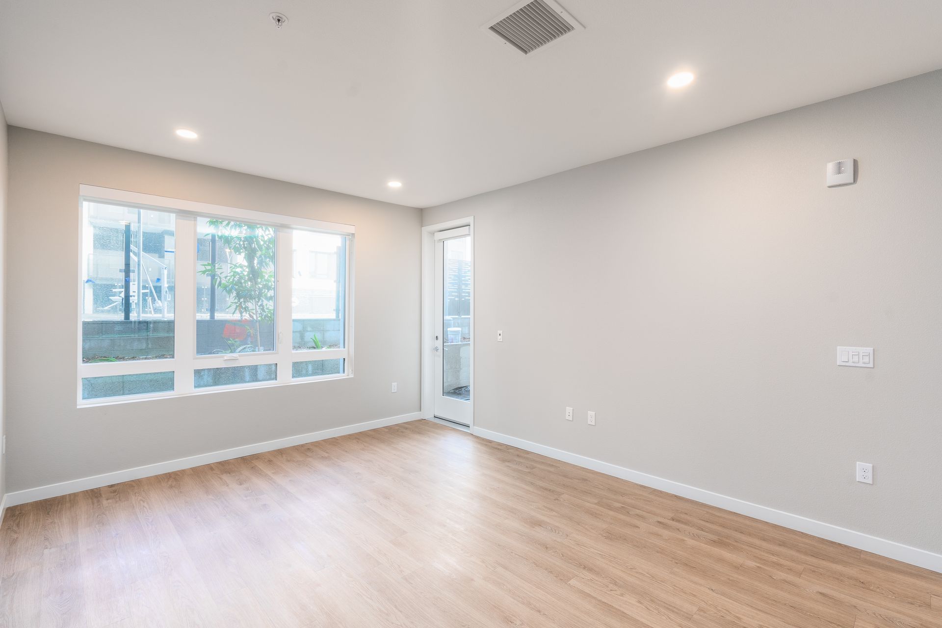 Empty room with wood floors, window, and door at Sofia, offers apartments in Santa Clara.