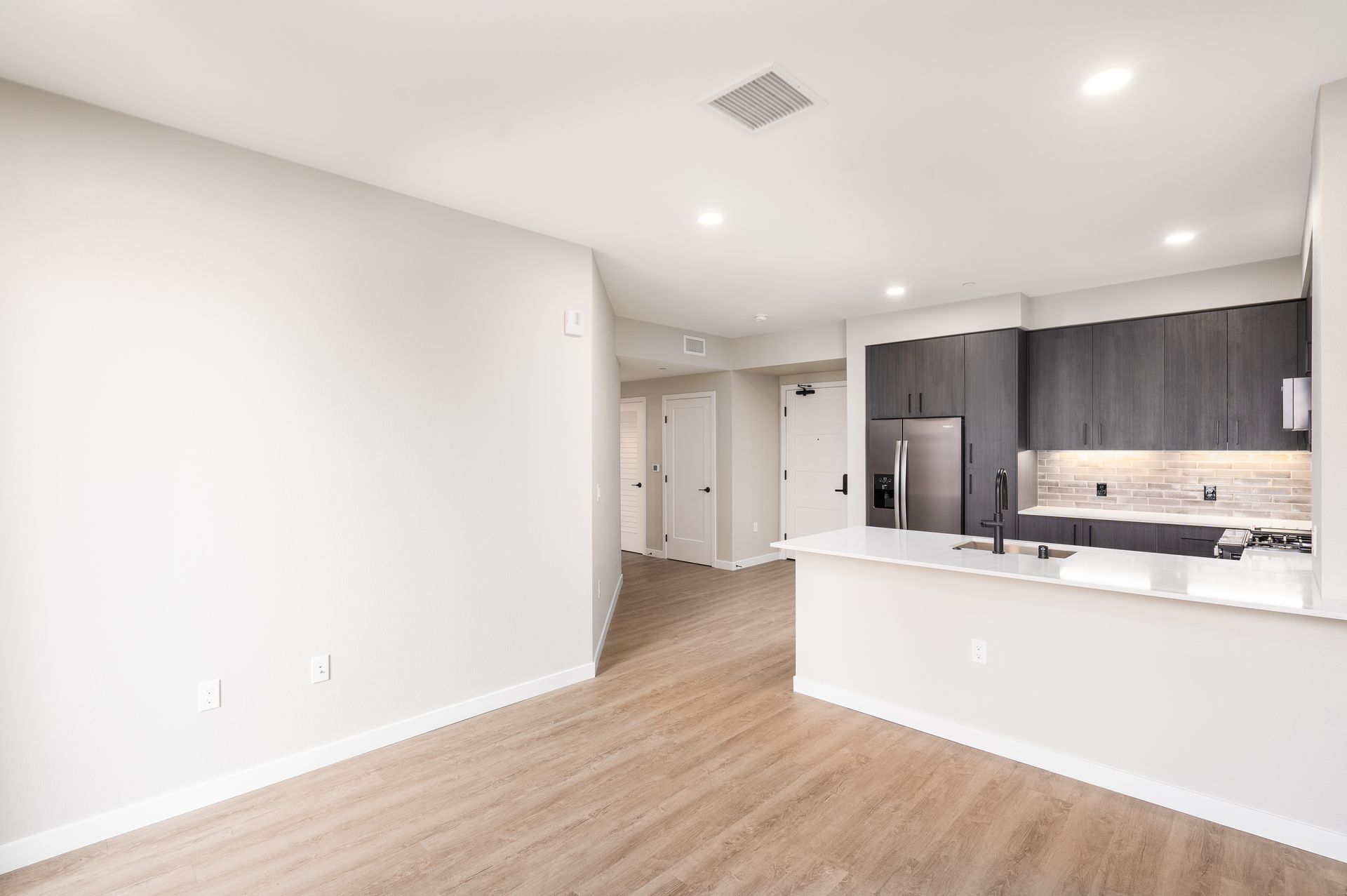 Modern open-concept apartment at Sofia with a kitchen, light wood floors, and neutral walls in Santa Clara.