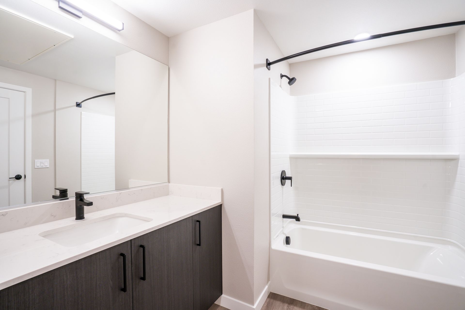 Modern bathroom with white walls, a bathtub, and dark gray vanity at Sofia, offers studio, 1, and 2 bedroom apartments in Santa Clara, CA.