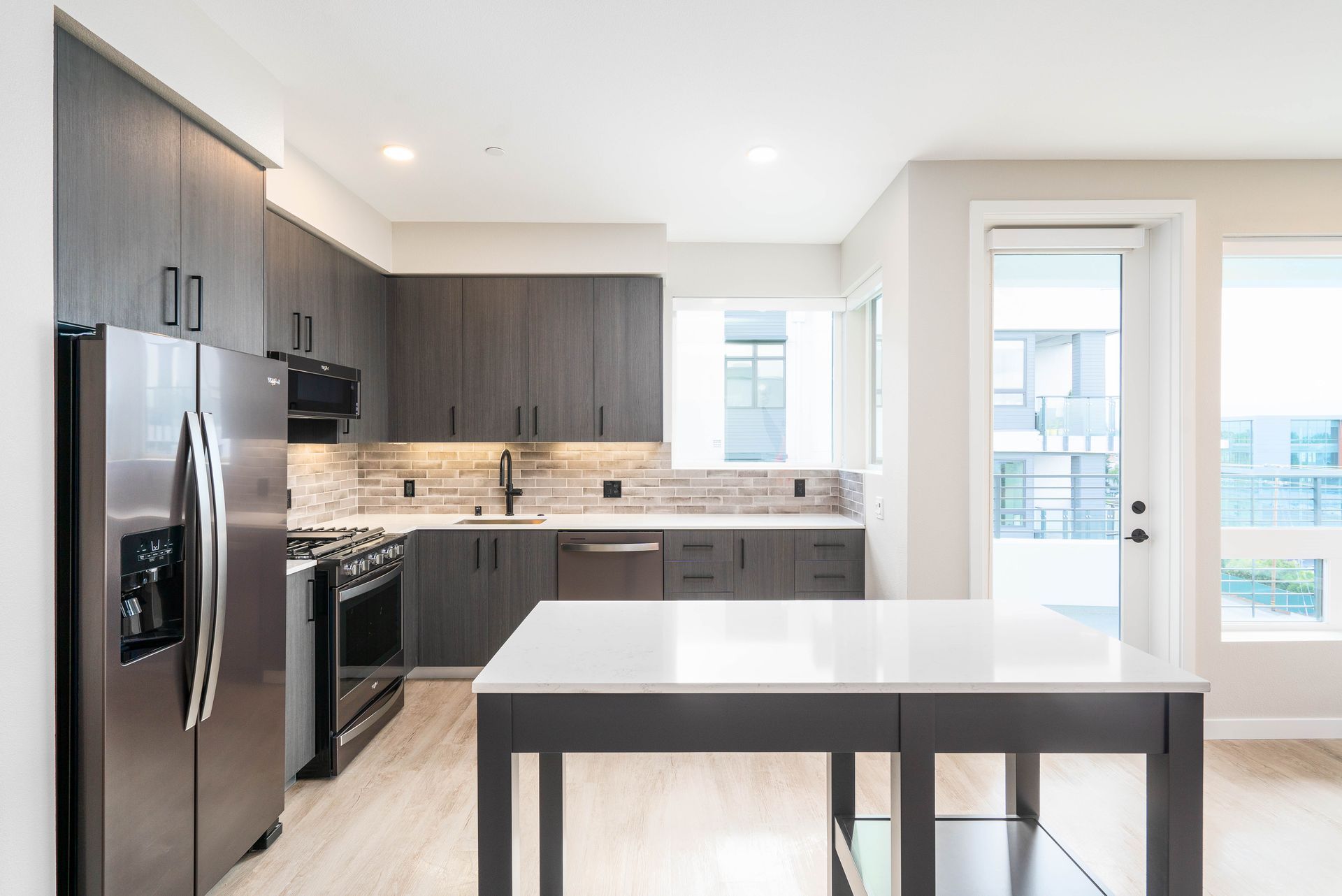 Modern kitchen with dark wood cabinets, stainless steel appliances, and a white island at Sofia, offers studio, 1, and 2 bedroom apartments in Santa Clara, CA.