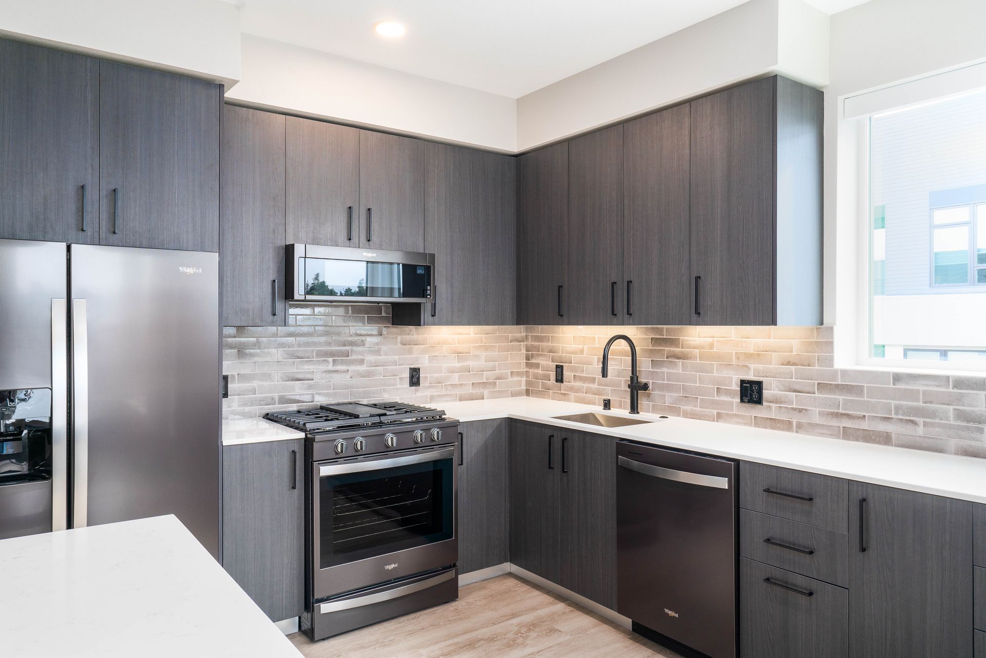 Modern kitchen with gray cabinets, stainless steel appliances, and white countertops at Sofia, offers studio, 1, and 2 bedroom apartments in Santa Clara, CA.