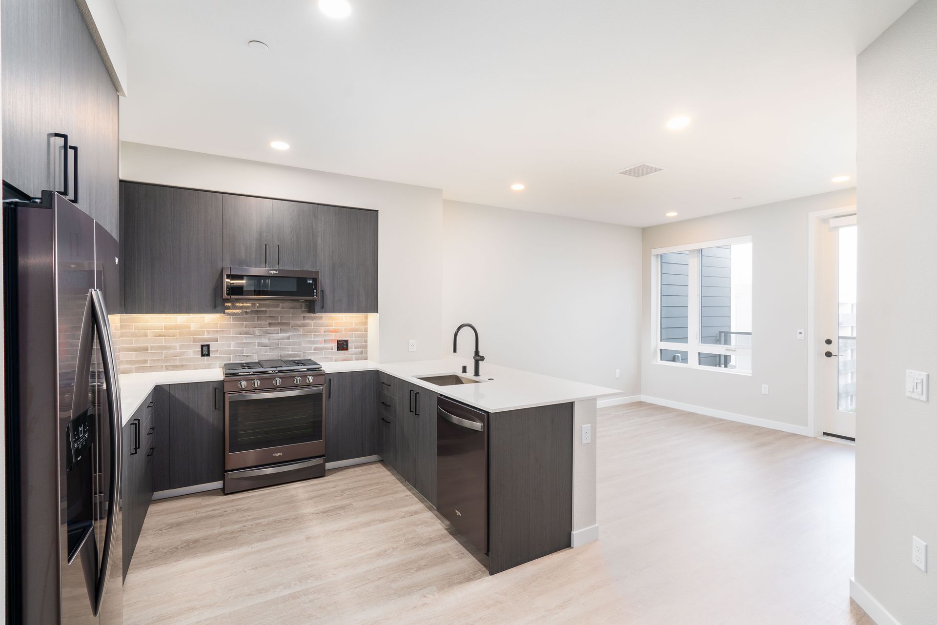 Modern kitchen with dark cabinetry, stainless steel appliances, and white countertops at Sofia, offers studio, 1, and 2 bedroom apartments in Santa Clara, CA.