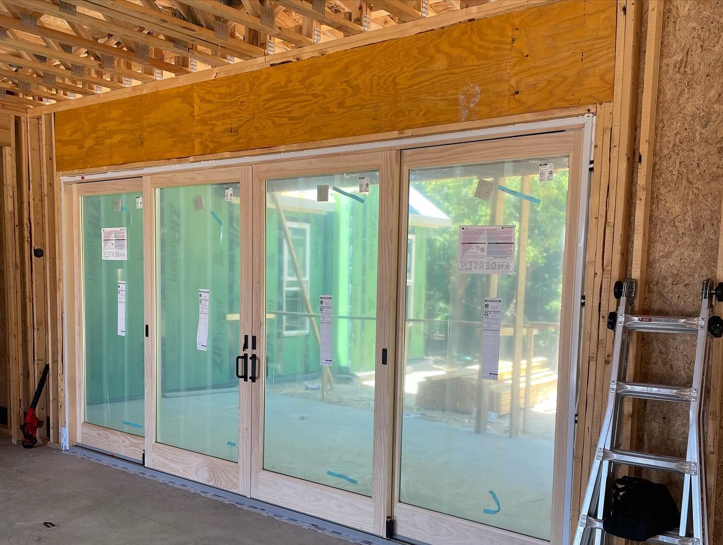 A ladder is sitting next to a large window in a building under construction.