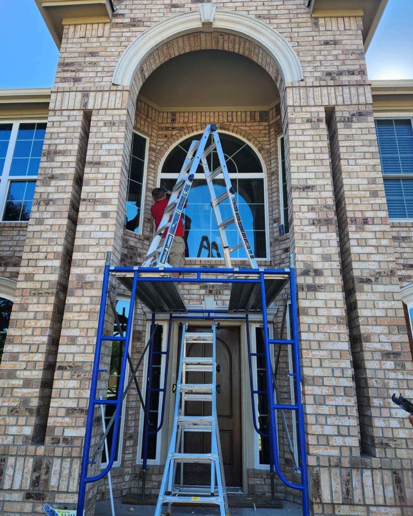 A ladder is sitting on top of a scaffolding in front of a brick building.