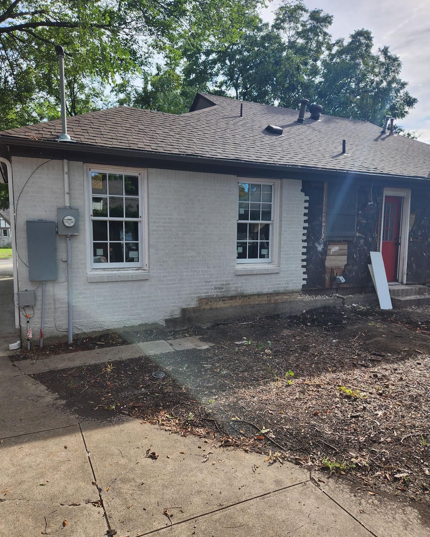 A white brick house with a brown roof and a lot of windows.