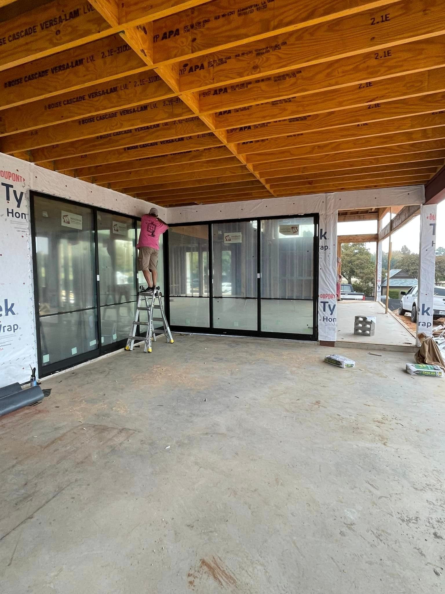 A man is standing on a ladder in a building under construction.