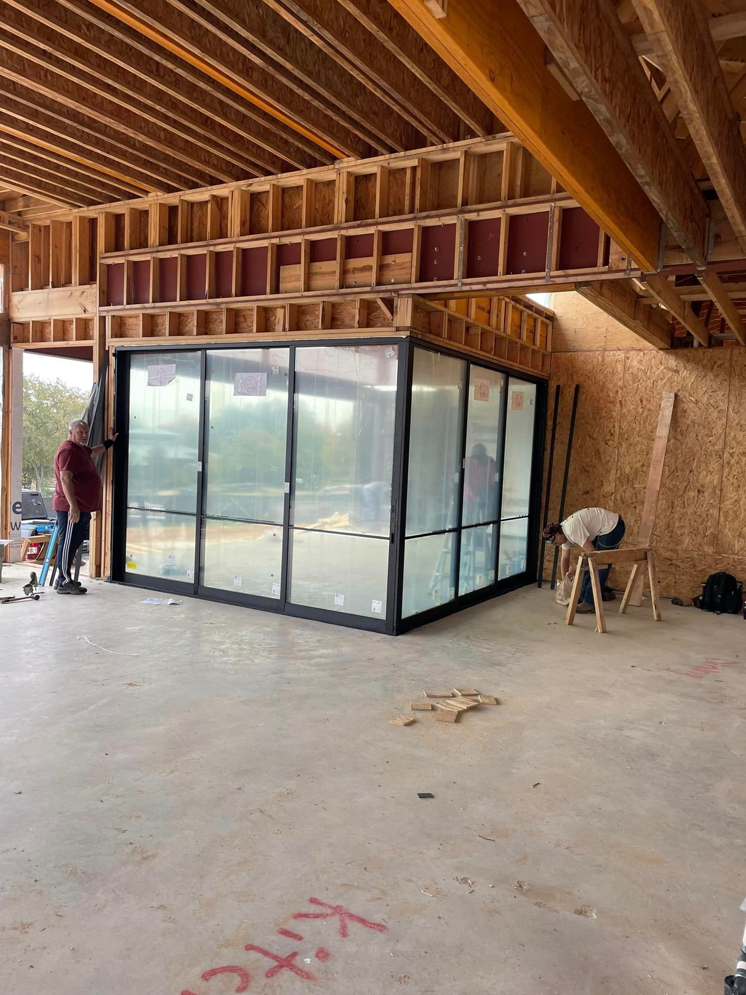 A building under construction with a lot of windows and sliding glass doors.