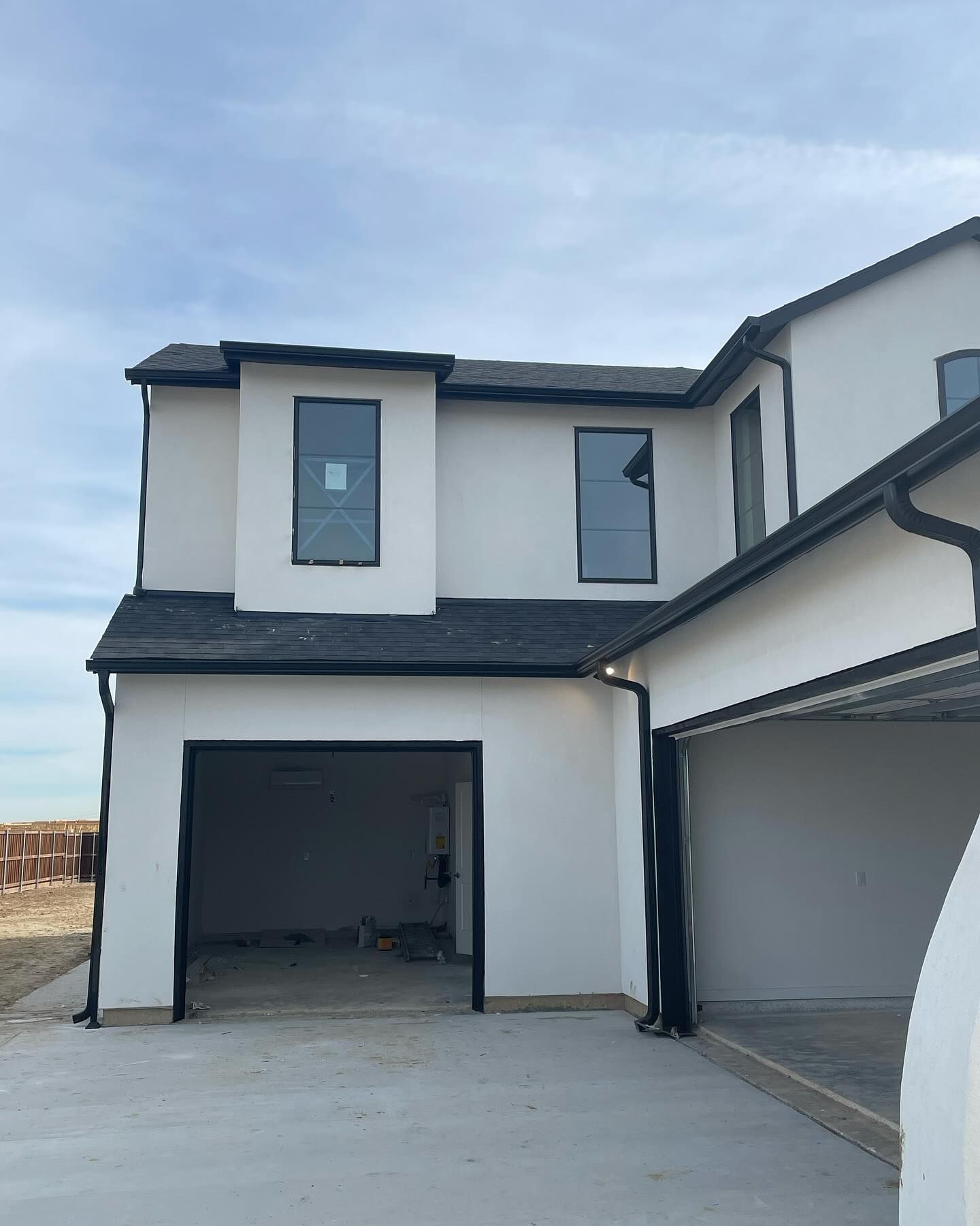A white house with a black roof and a garage