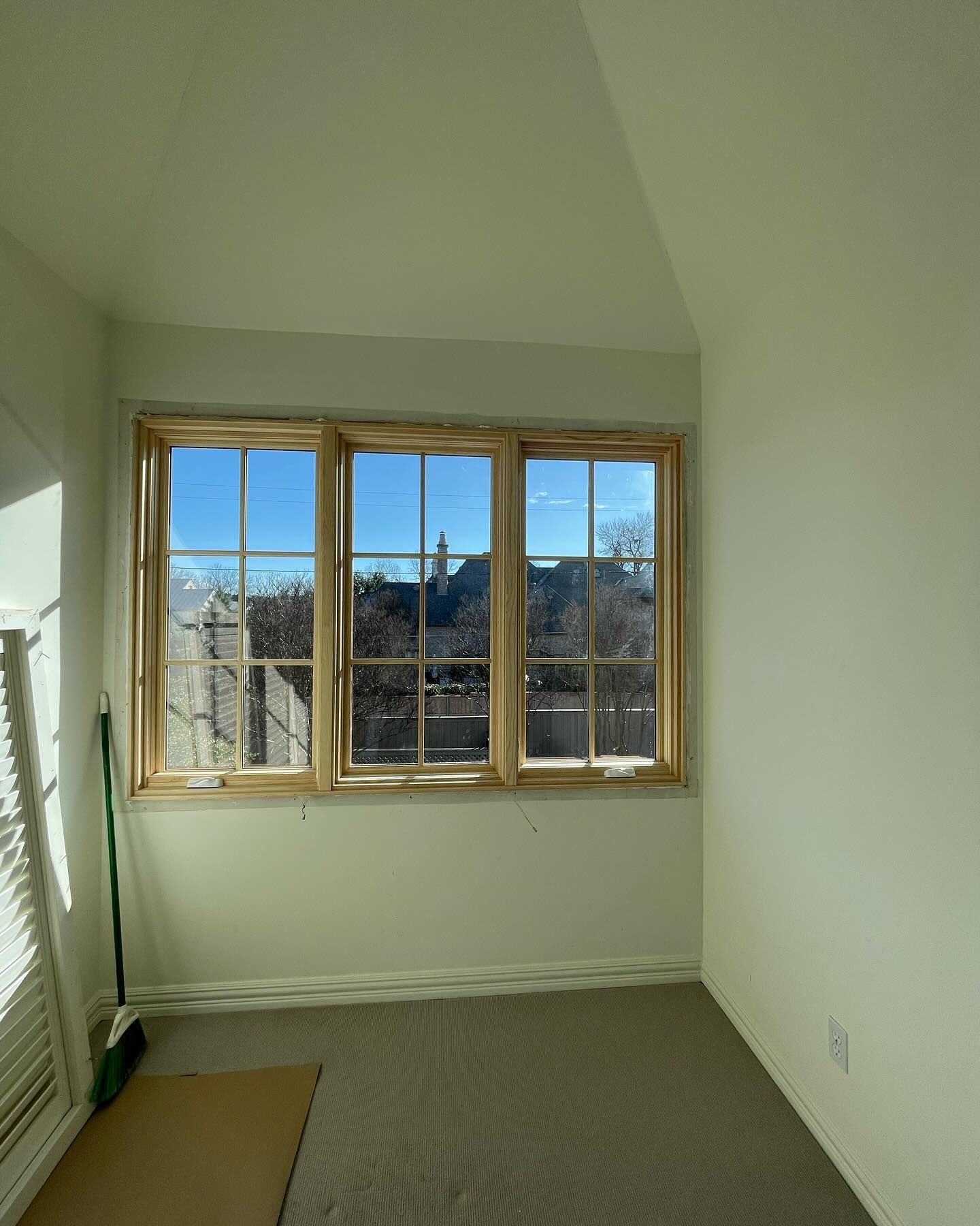 An empty room with a large window and a broom.