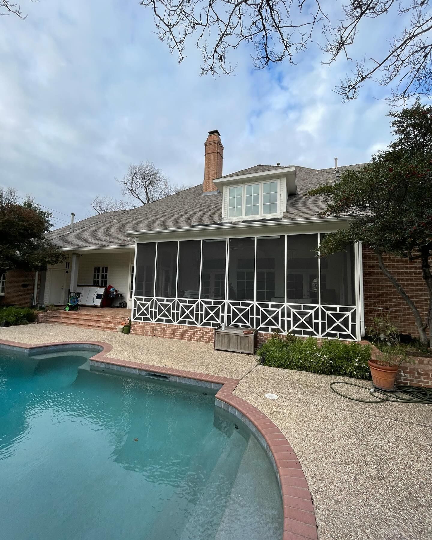 A screened in porch with a swimming pool in front of it.