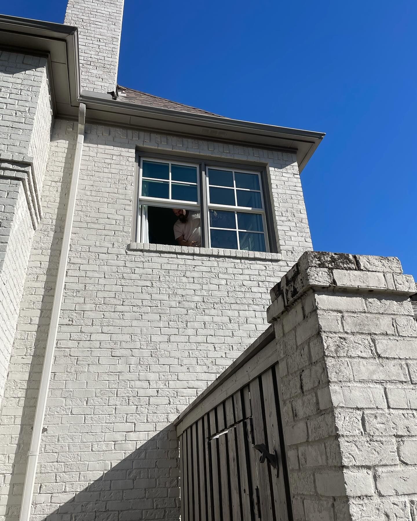A white brick building with a dog looking out of a window