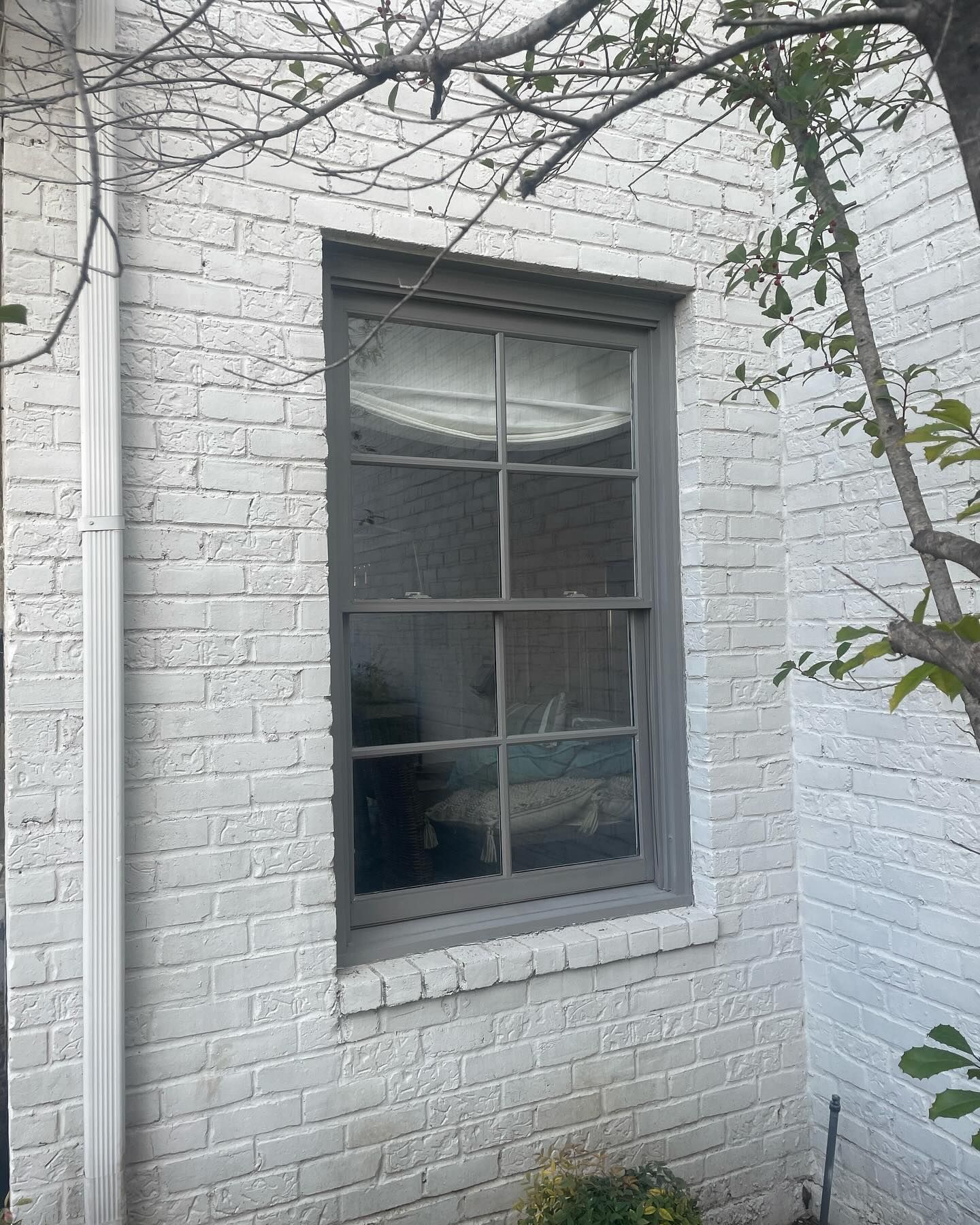A white brick building with a window on the side of it.