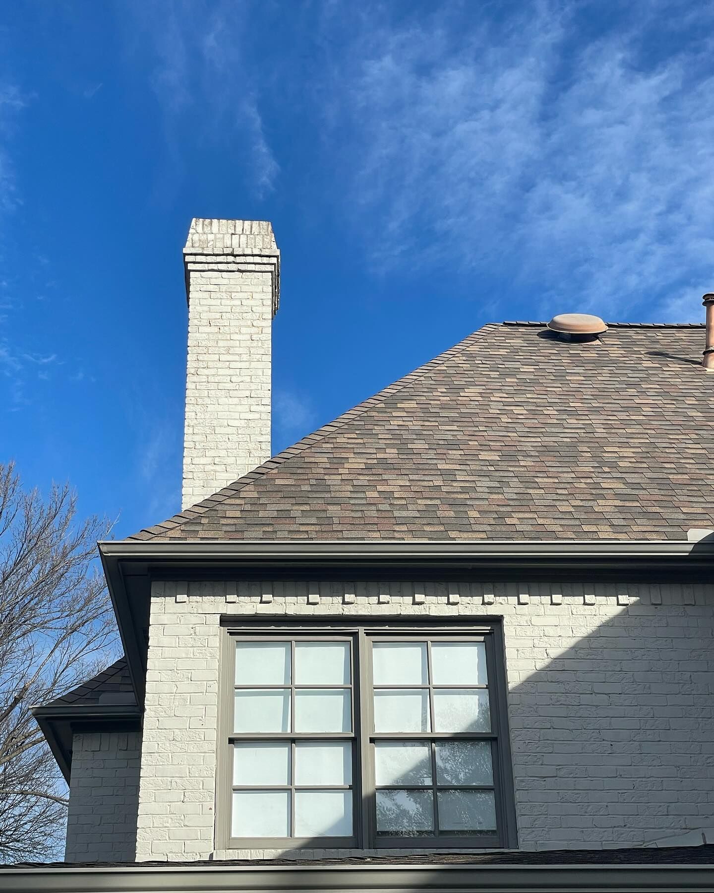 A white brick house with a chimney and a window