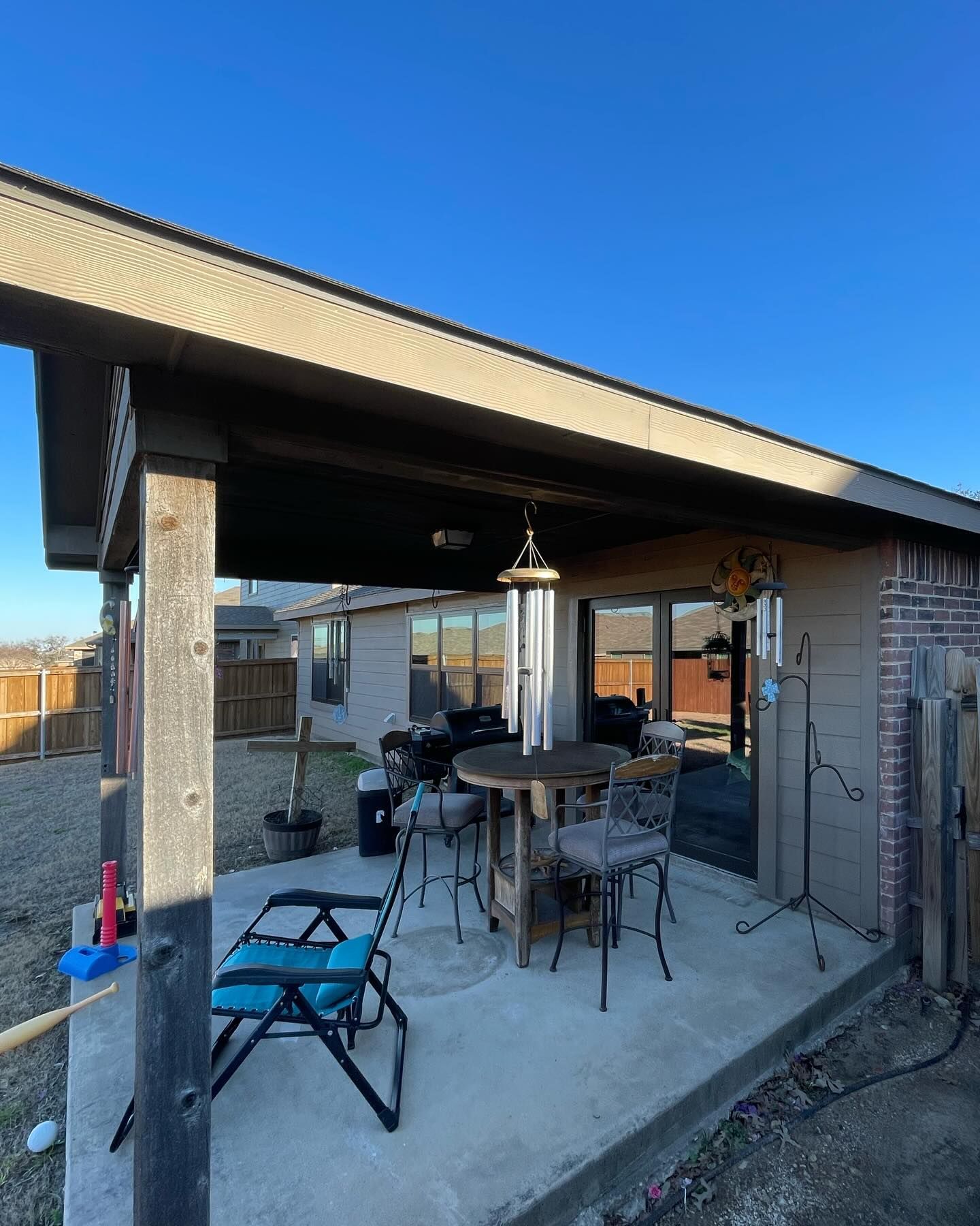 A patio area with a table and chairs under a covered roof.