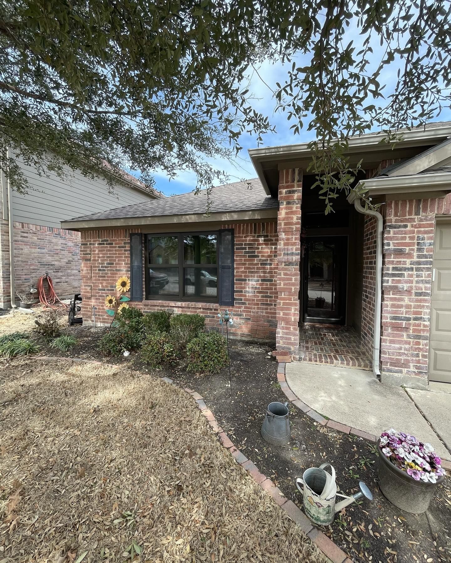 A brick house with a garden and a watering can in front of it.