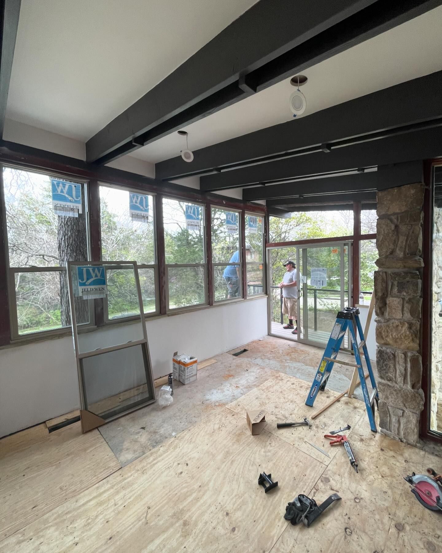 A room with a lot of windows and a ladder on the floor.