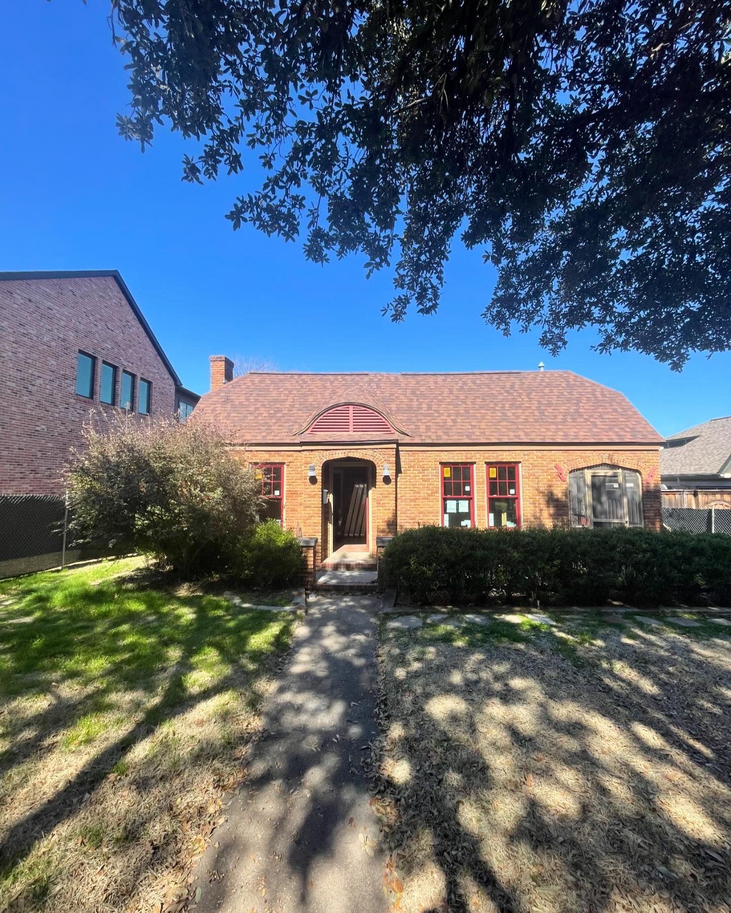 A brick house with a red roof and a walkway leading to it.