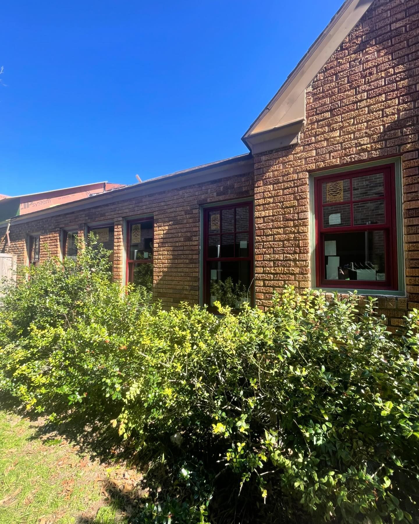 A brick building with a lot of windows and bushes in front of it