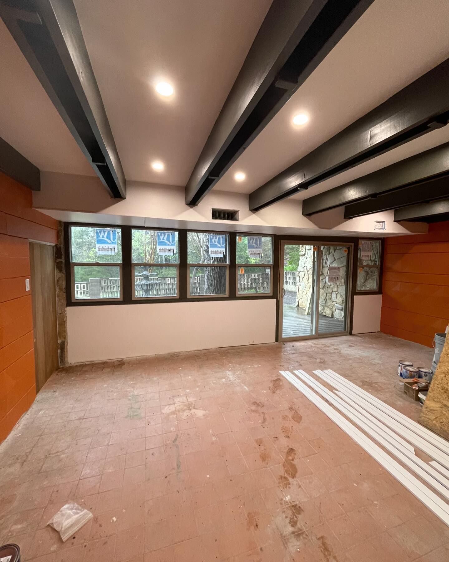 An empty room with a lot of windows and a ceiling with beams.