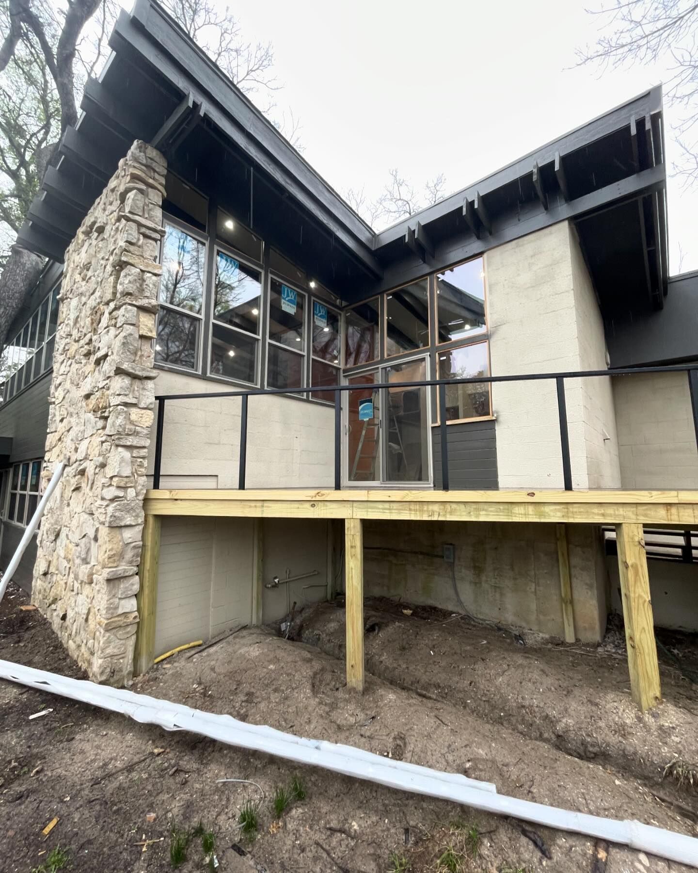 A large house with a wooden deck and a stone chimney.