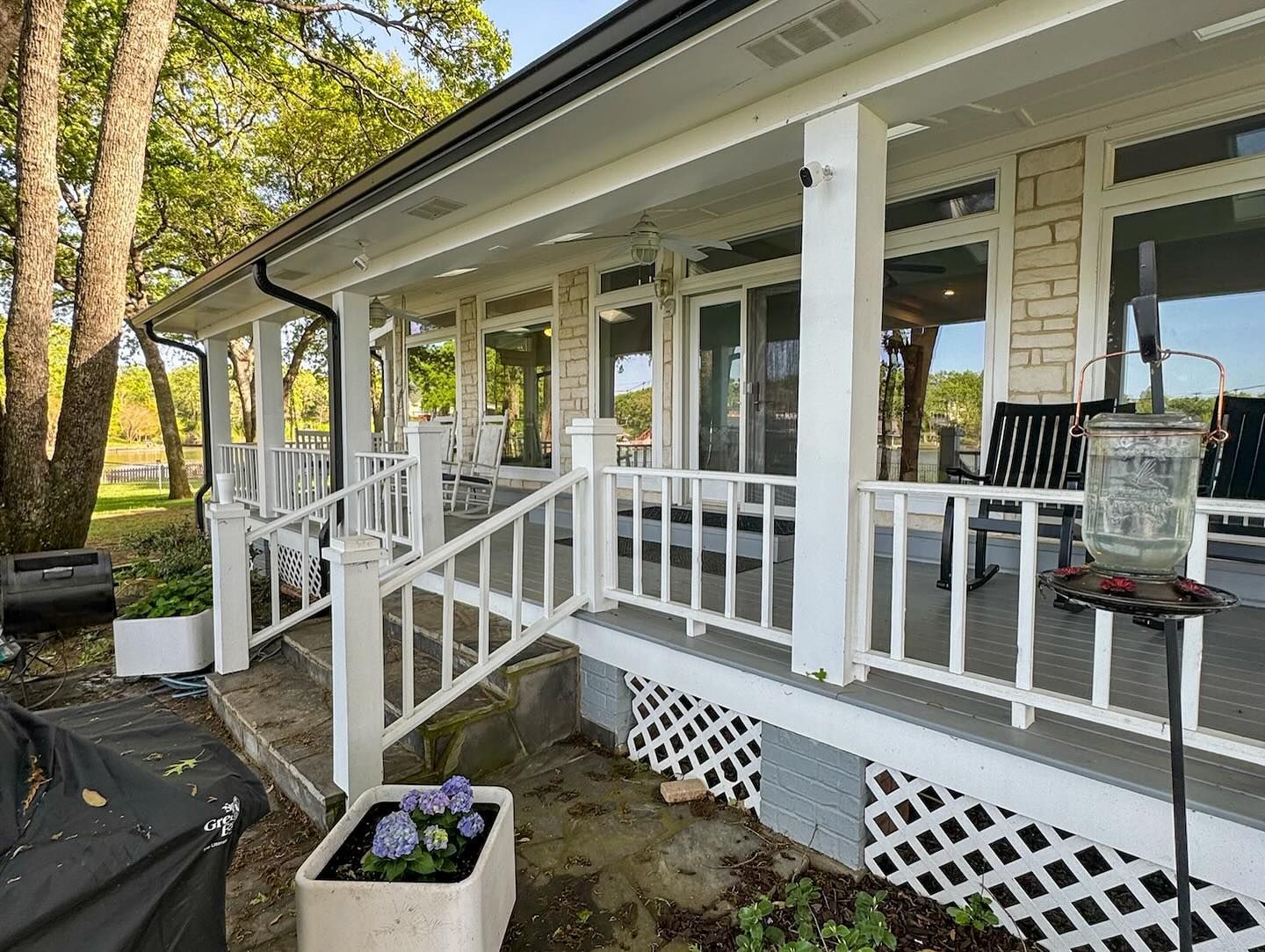 A large white porch with a bird feeder on it.