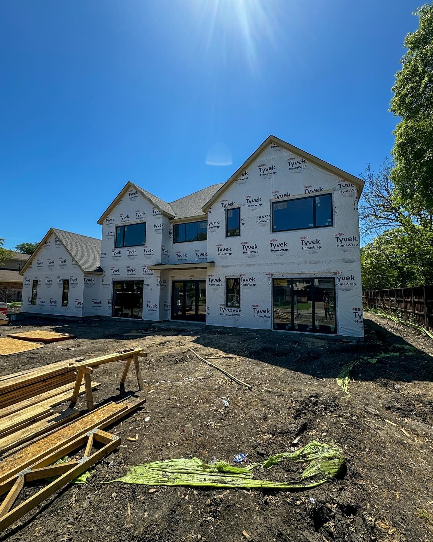 A large house is being built in the middle of a dirt field.