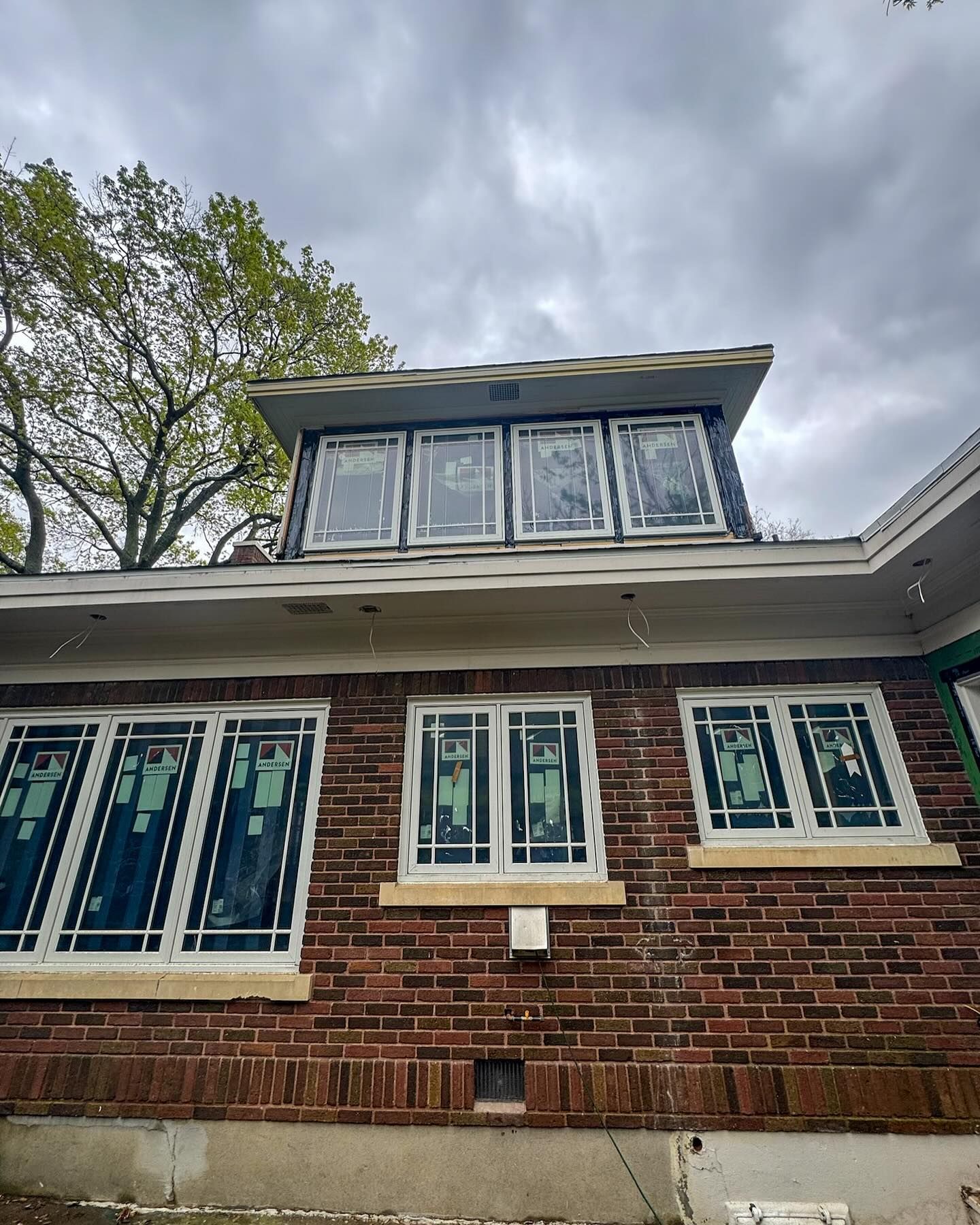 A brick house with a lot of windows and a roof.
