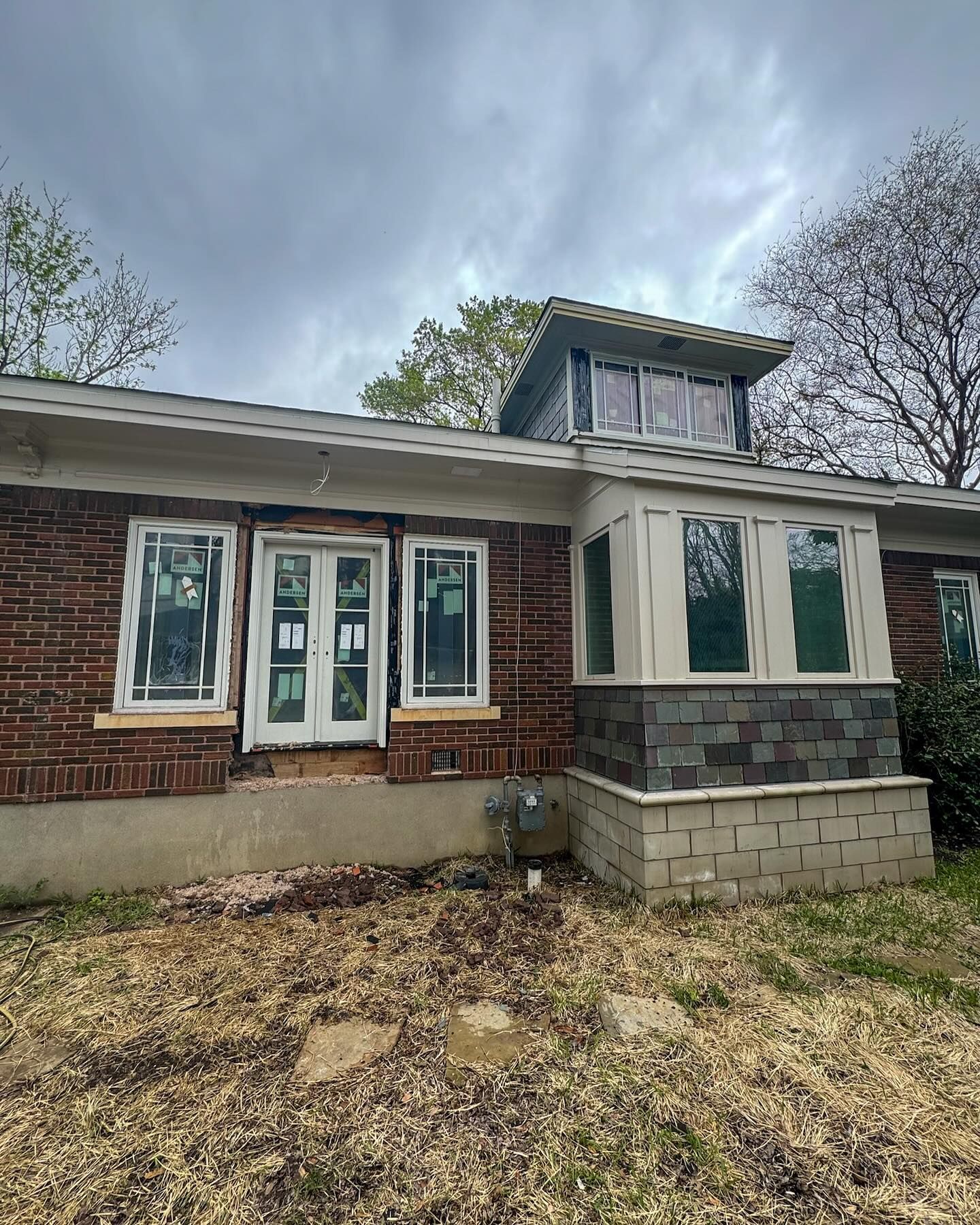 A brick house with a lot of windows is being remodeled.