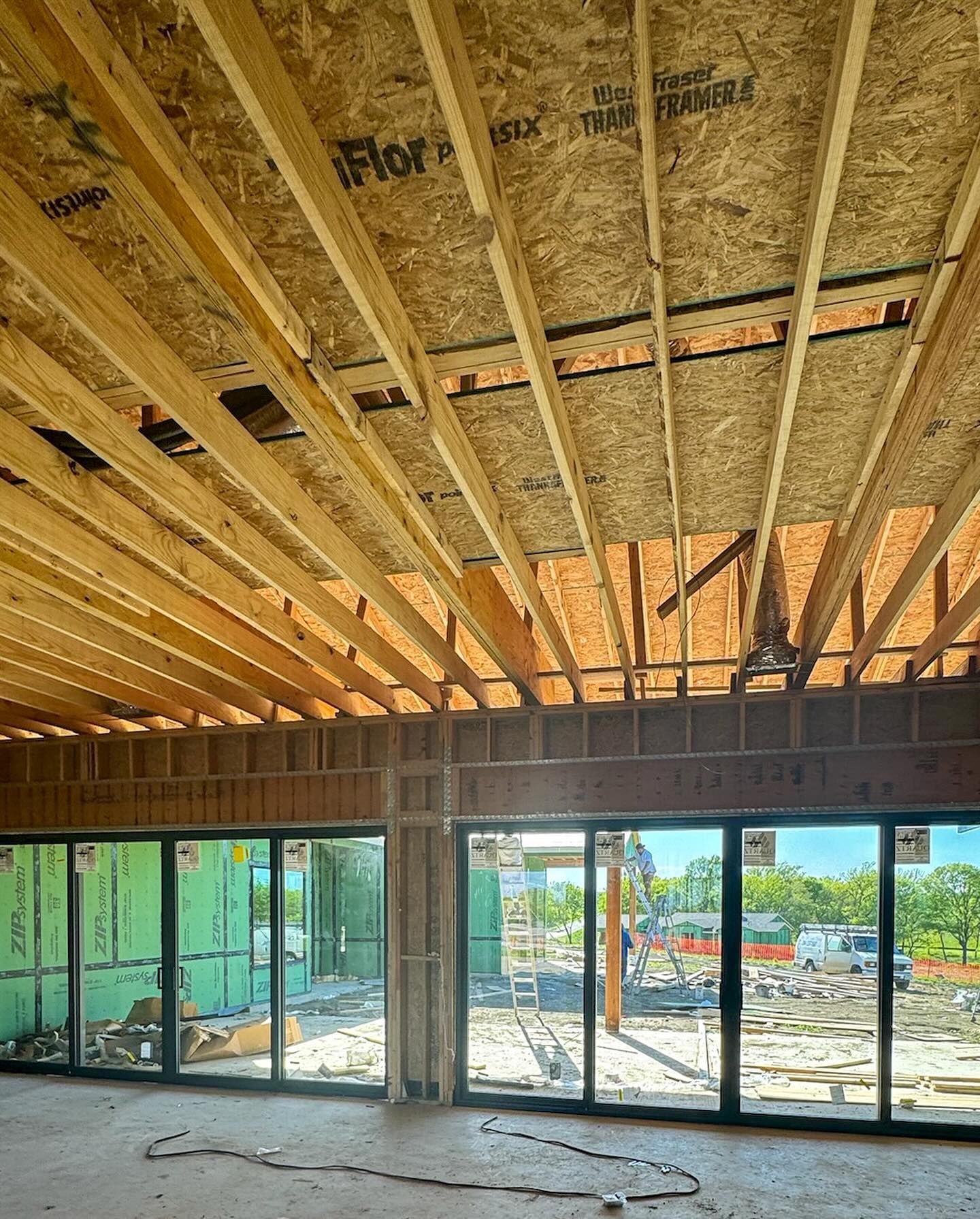 A room under construction with a lot of windows and wooden beams.