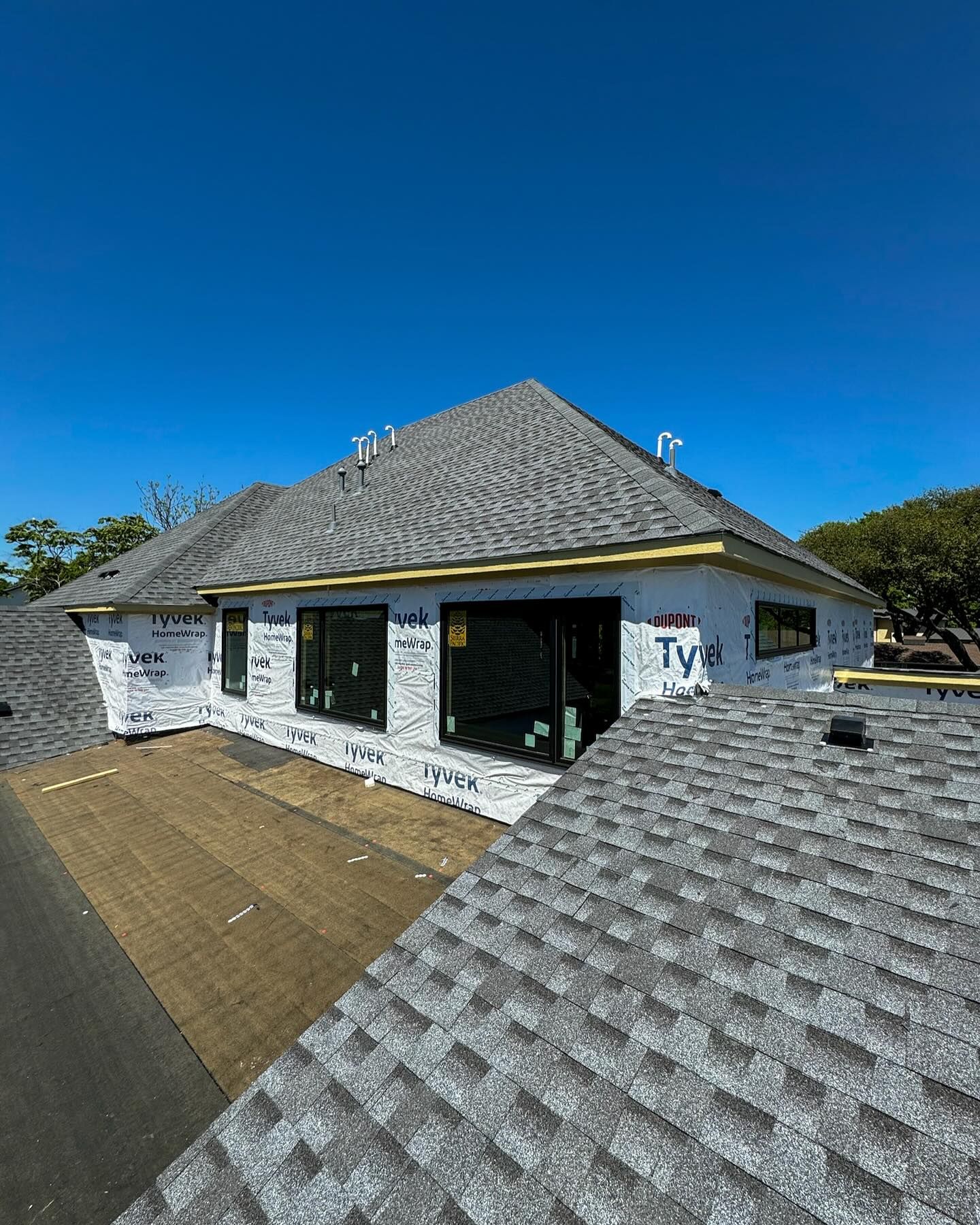 A house with a gray roof is being built.
