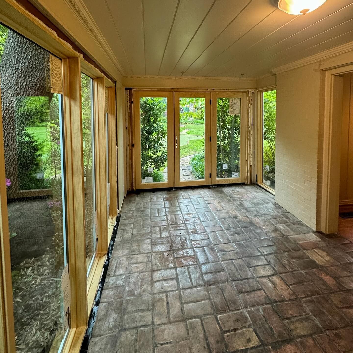 A room with a brick floor and lots of windows