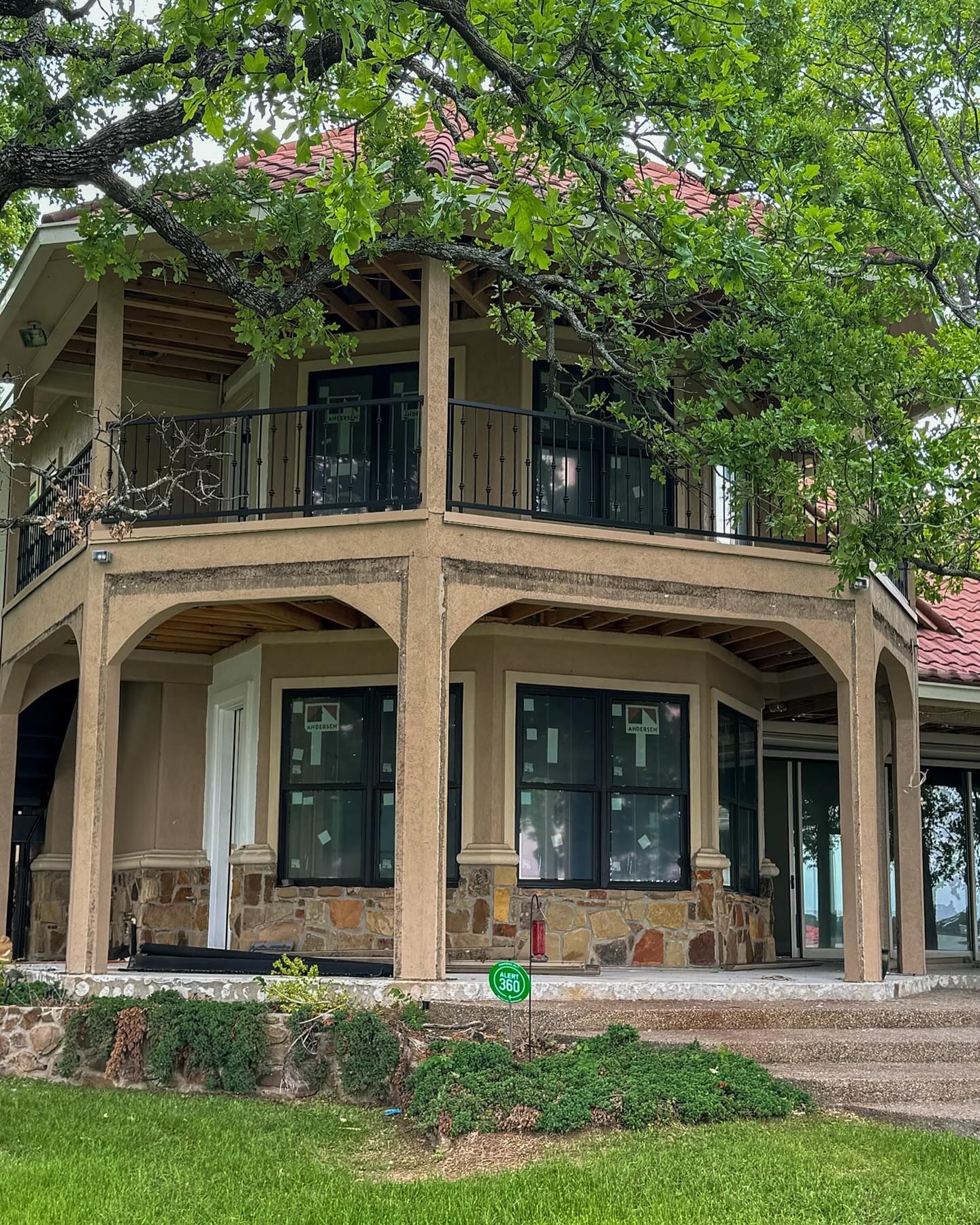 A large house with a lot of windows is sitting on top of a lush green field.