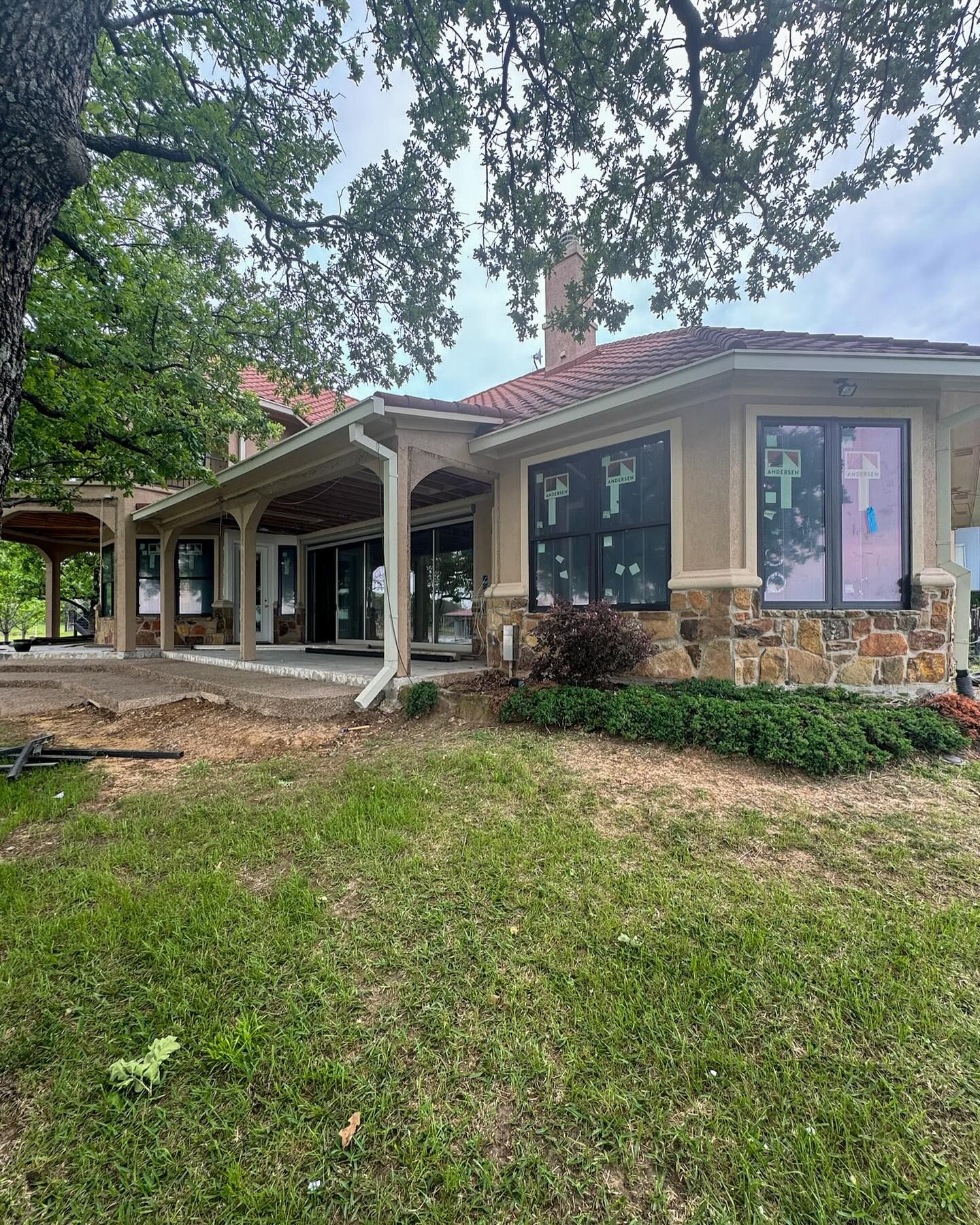 A large house with a lot of windows is sitting on top of a lush green field.