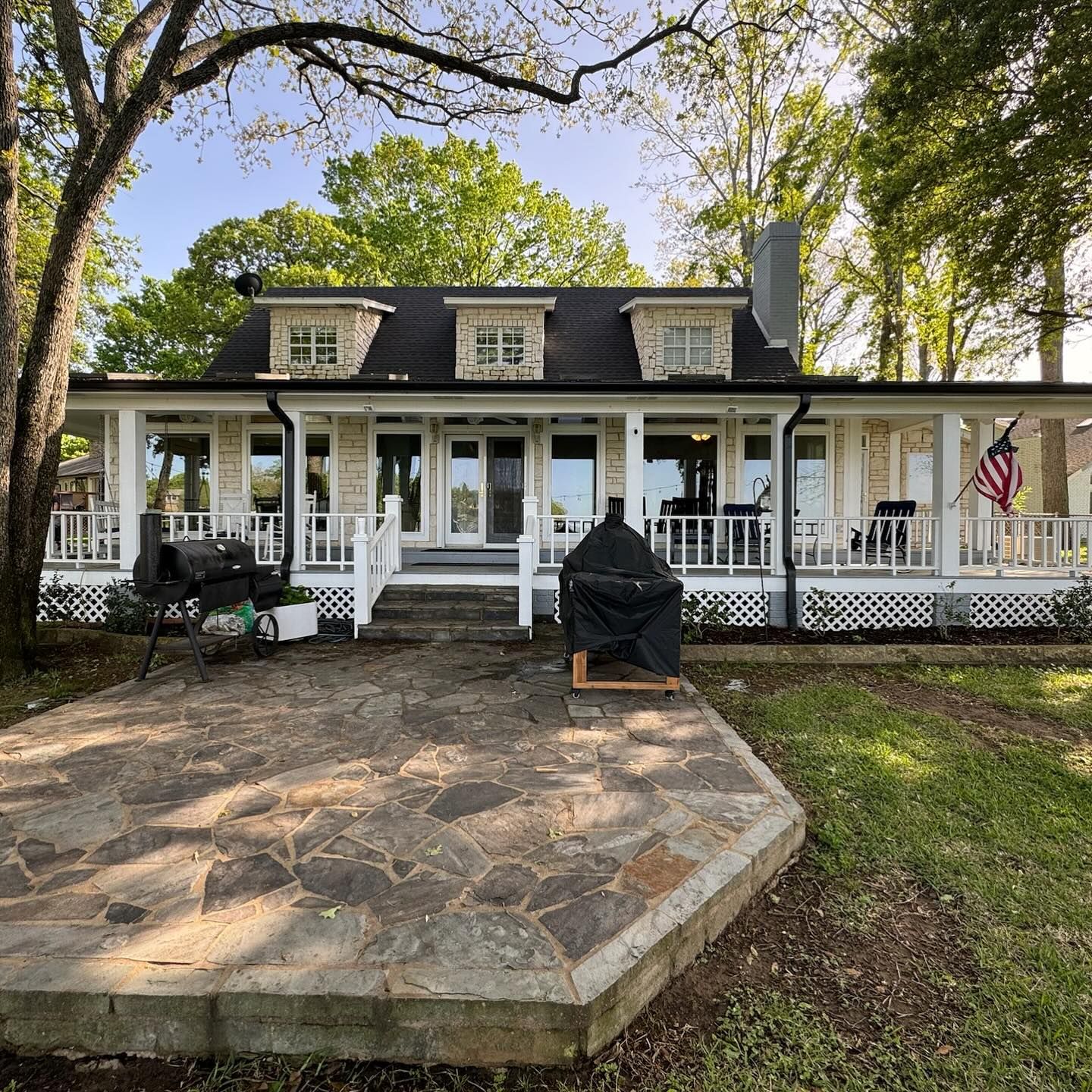 A white house with a black roof and a large porch