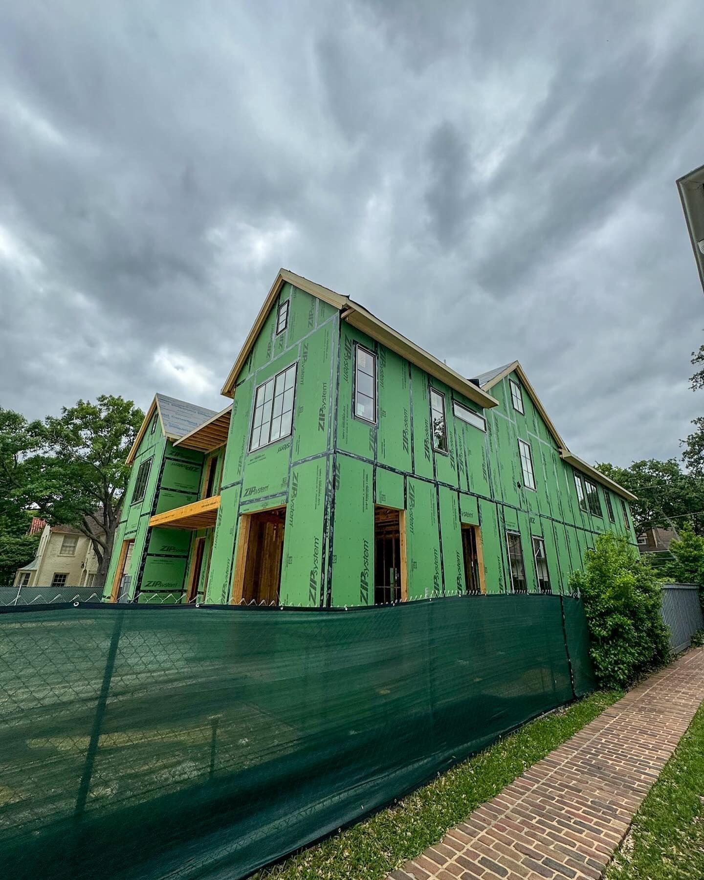 A green house is being built next to a green fence.