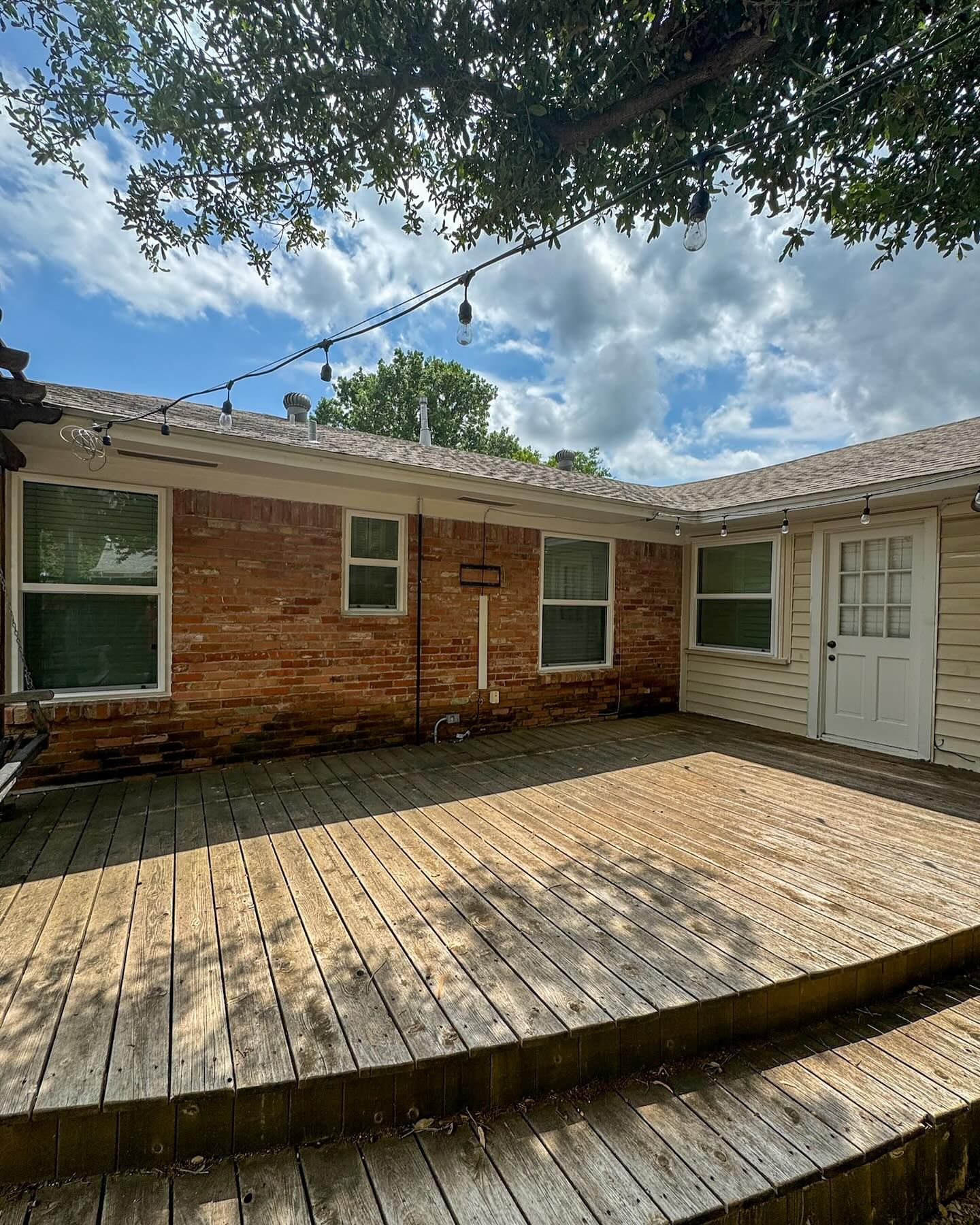 A brick house with a wooden deck in front of it.