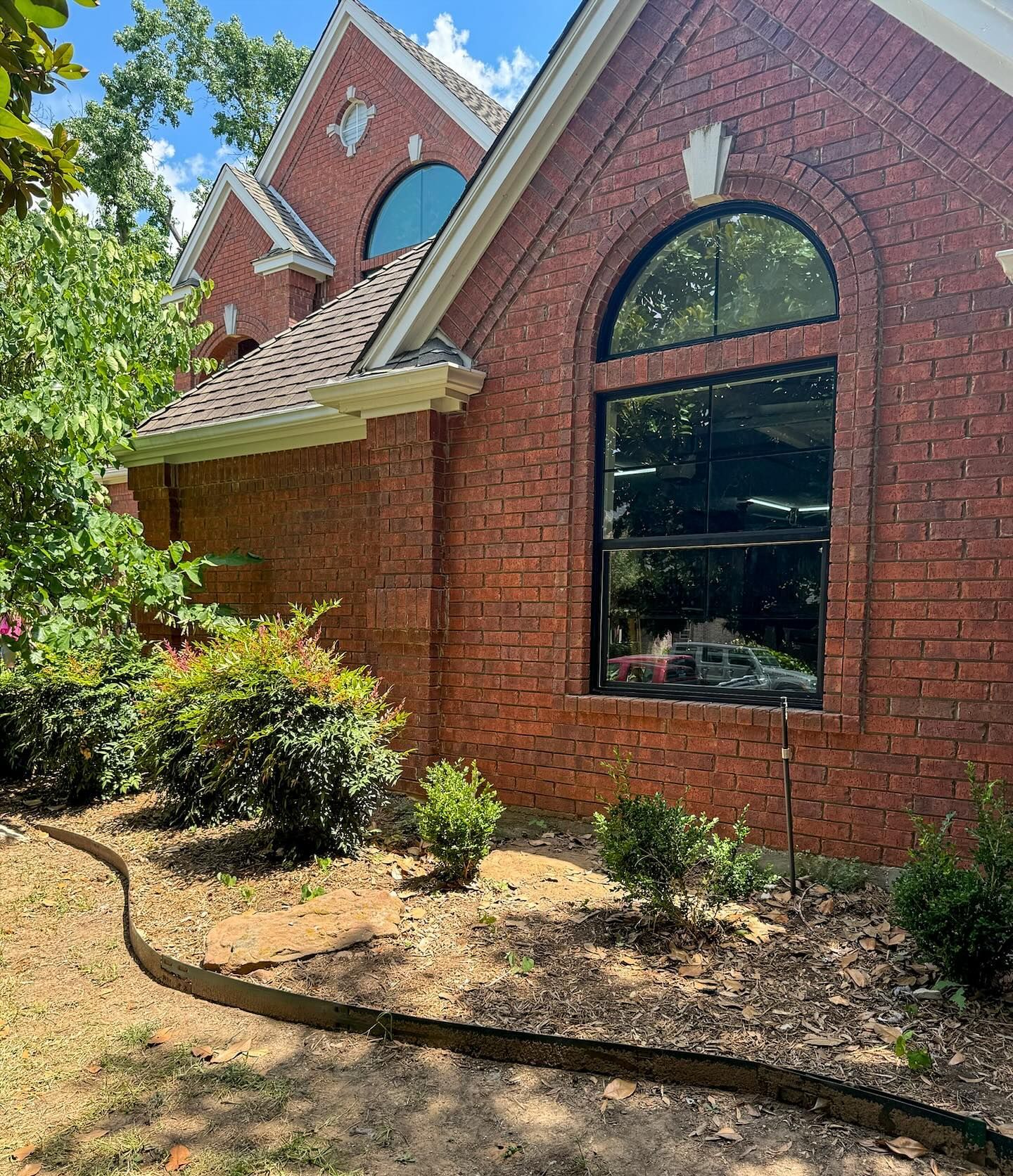 A large brick house with a lot of windows and bushes in front of it.