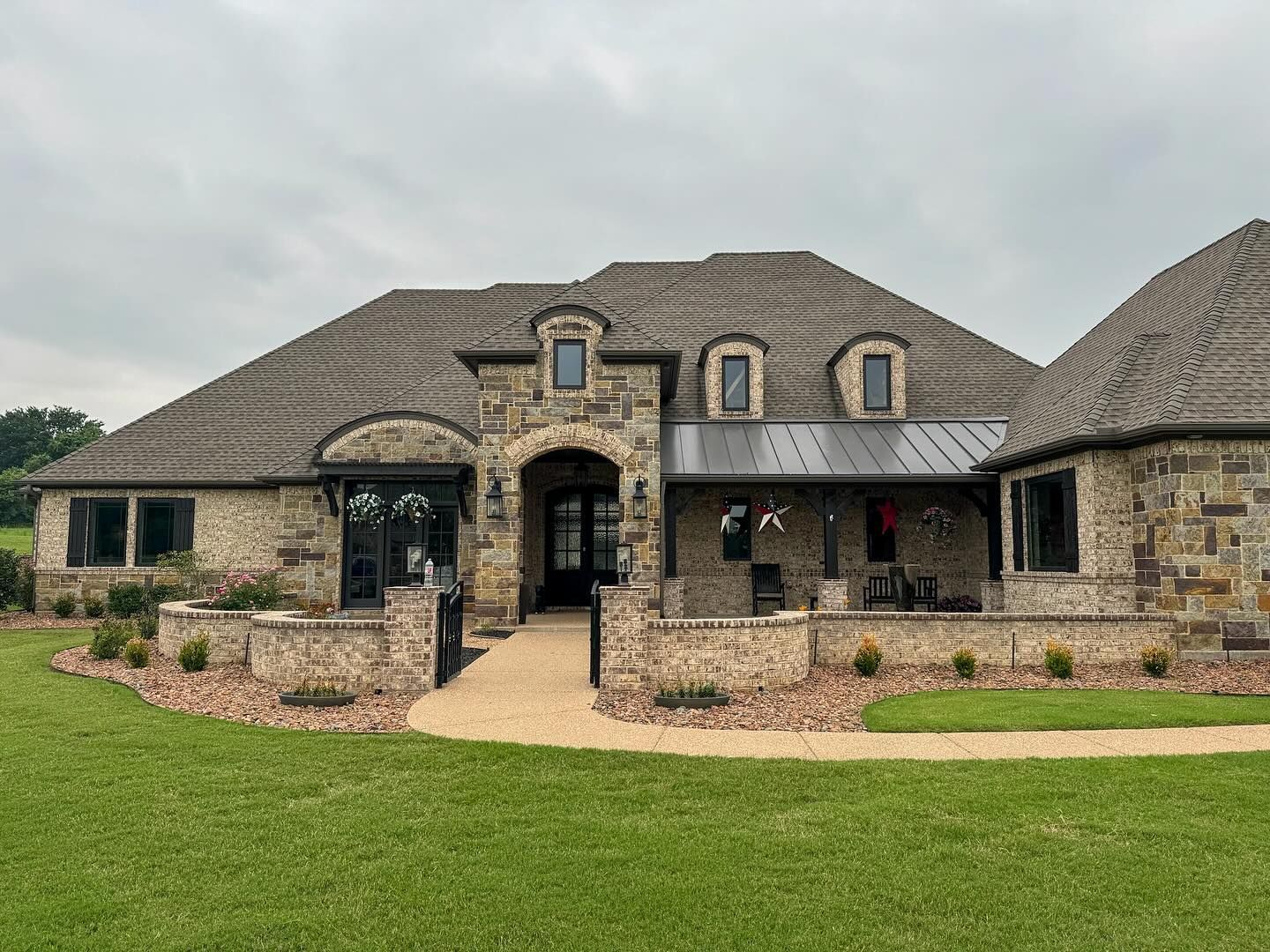 A large stone house with a large lawn in front of it.