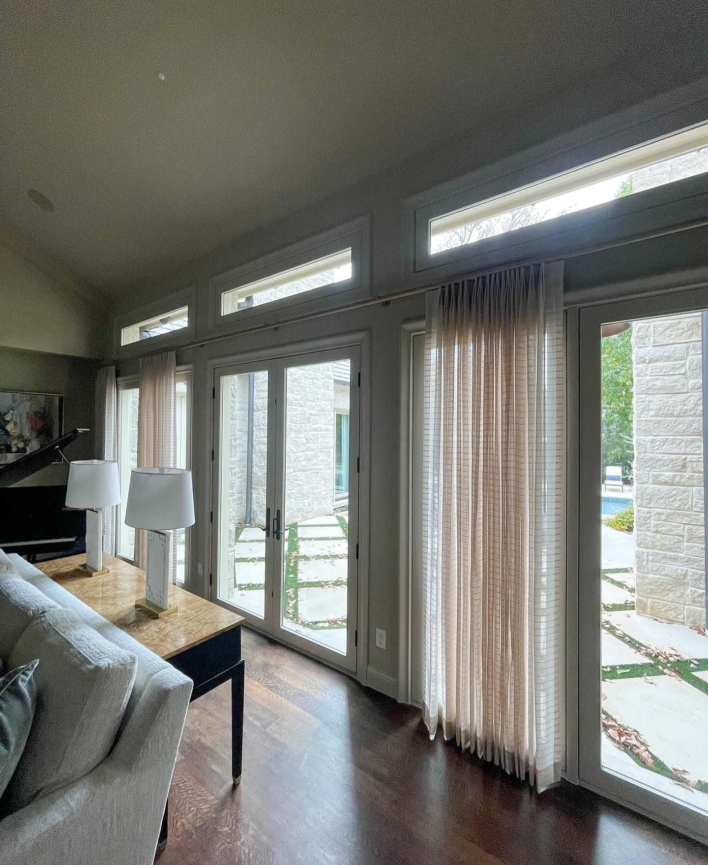 A living room with a couch , table , lamps and sliding glass doors.