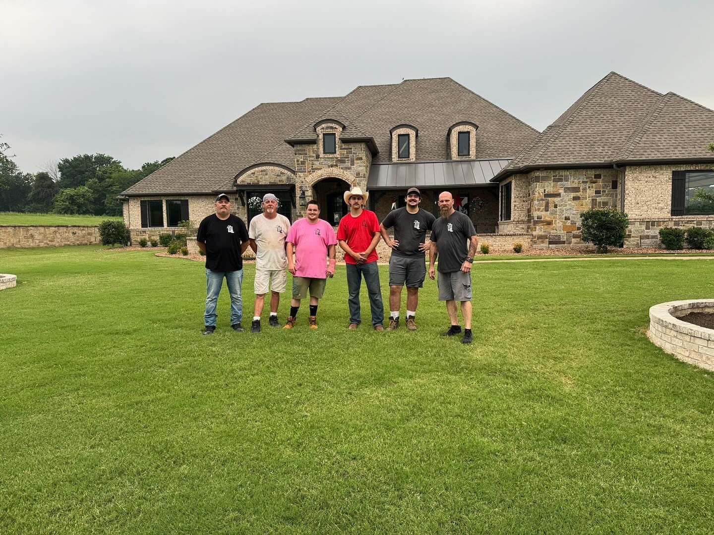 A group of men are standing in front of a large house.