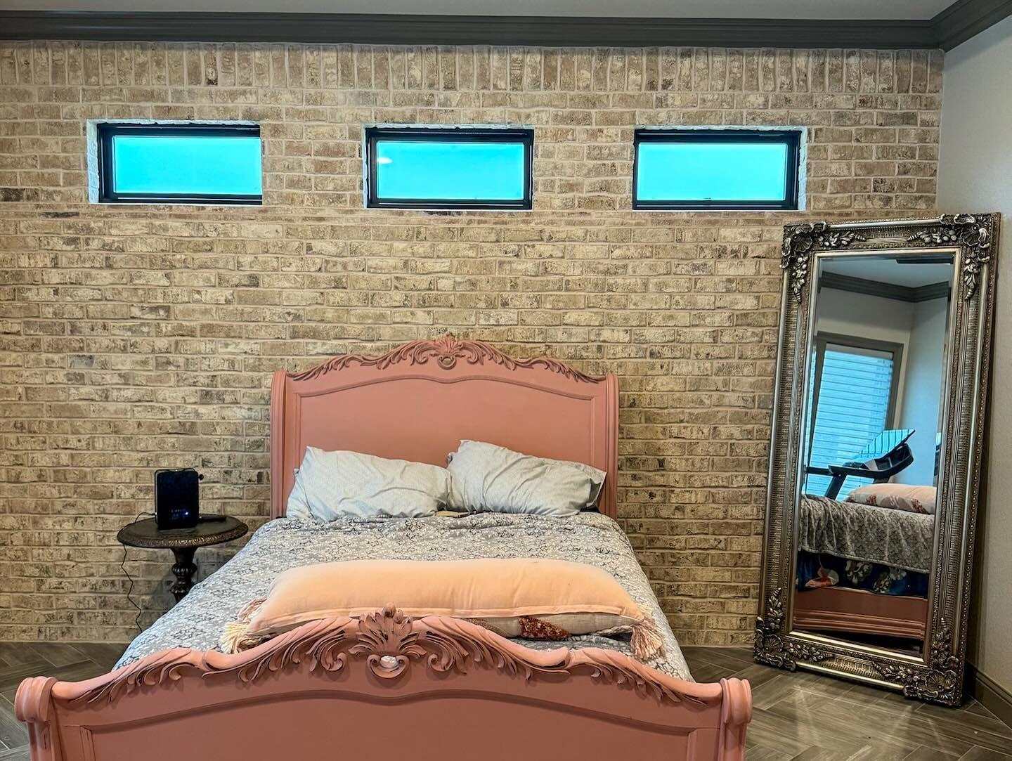 A bedroom with a bed , mirror and brick wall.