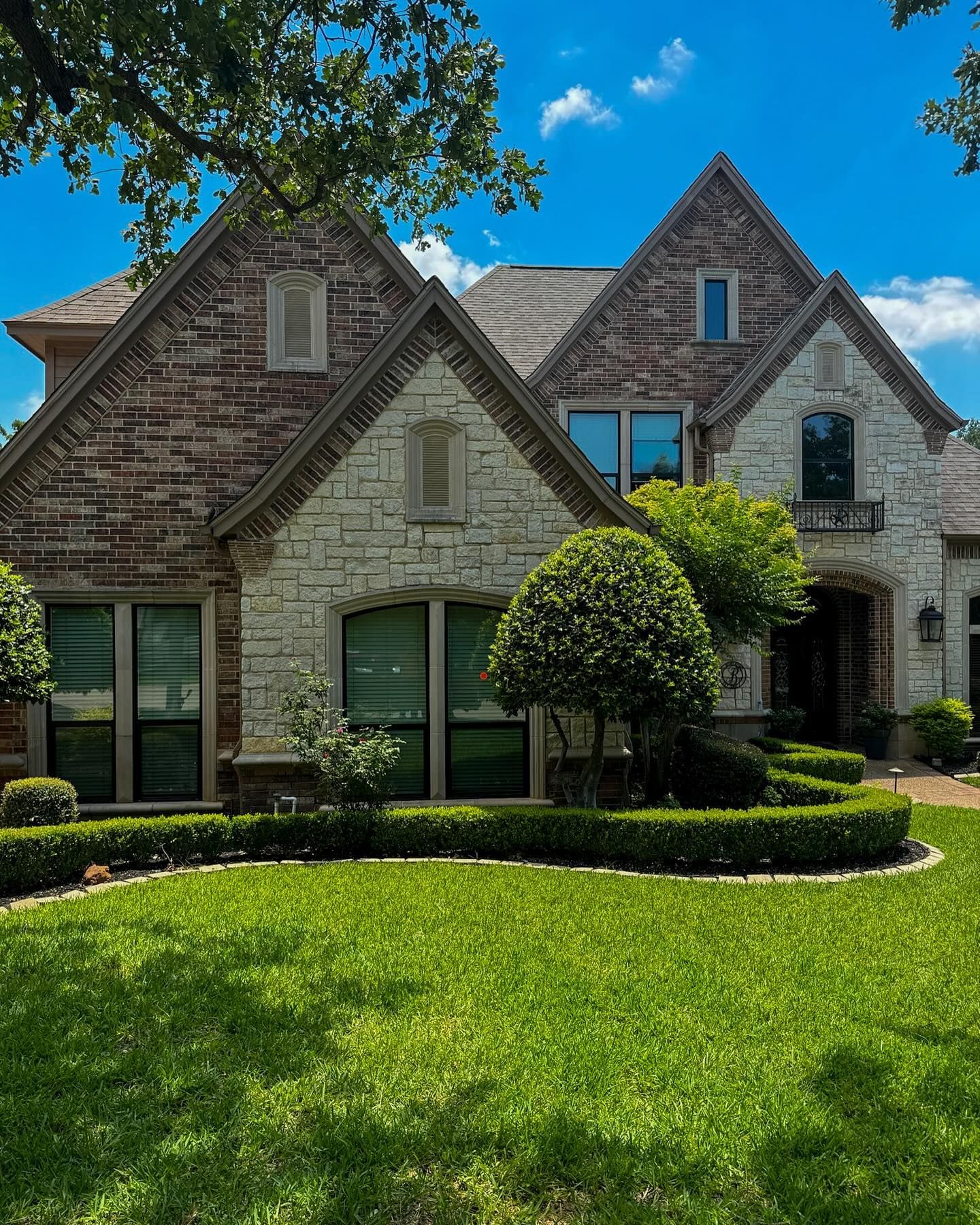 A large brick house with a lush green lawn in front of it.