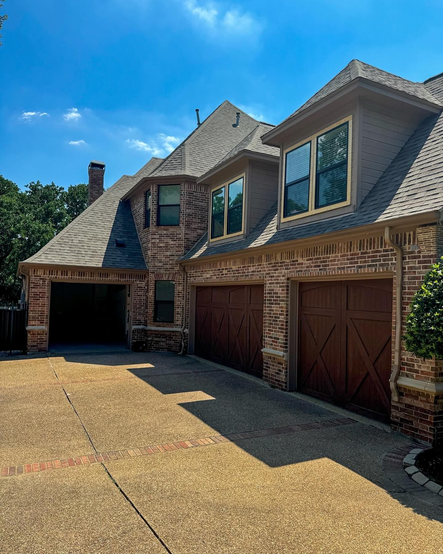 A large brick house with two garage doors and a driveway.