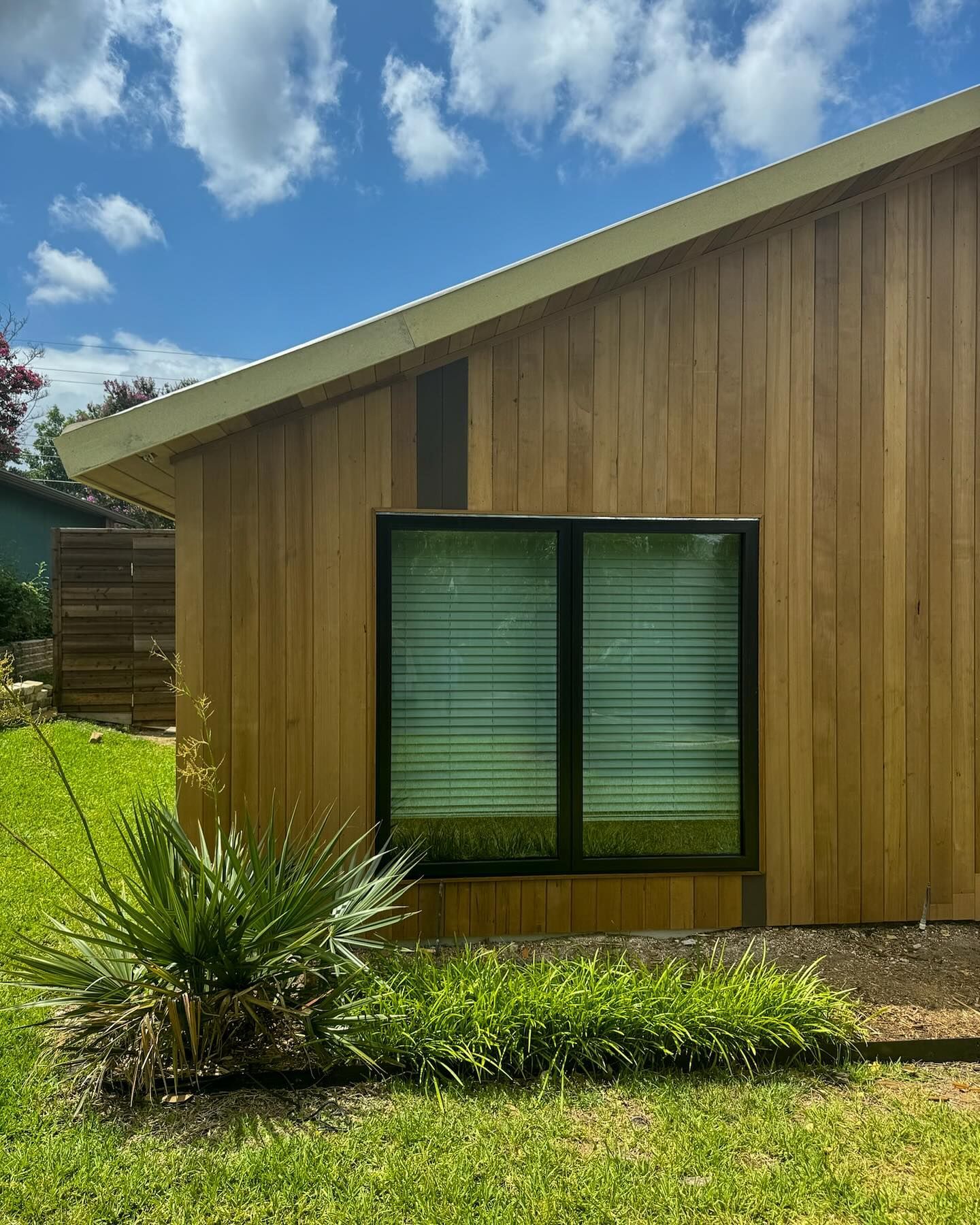 A small wooden house with a large window in the backyard.